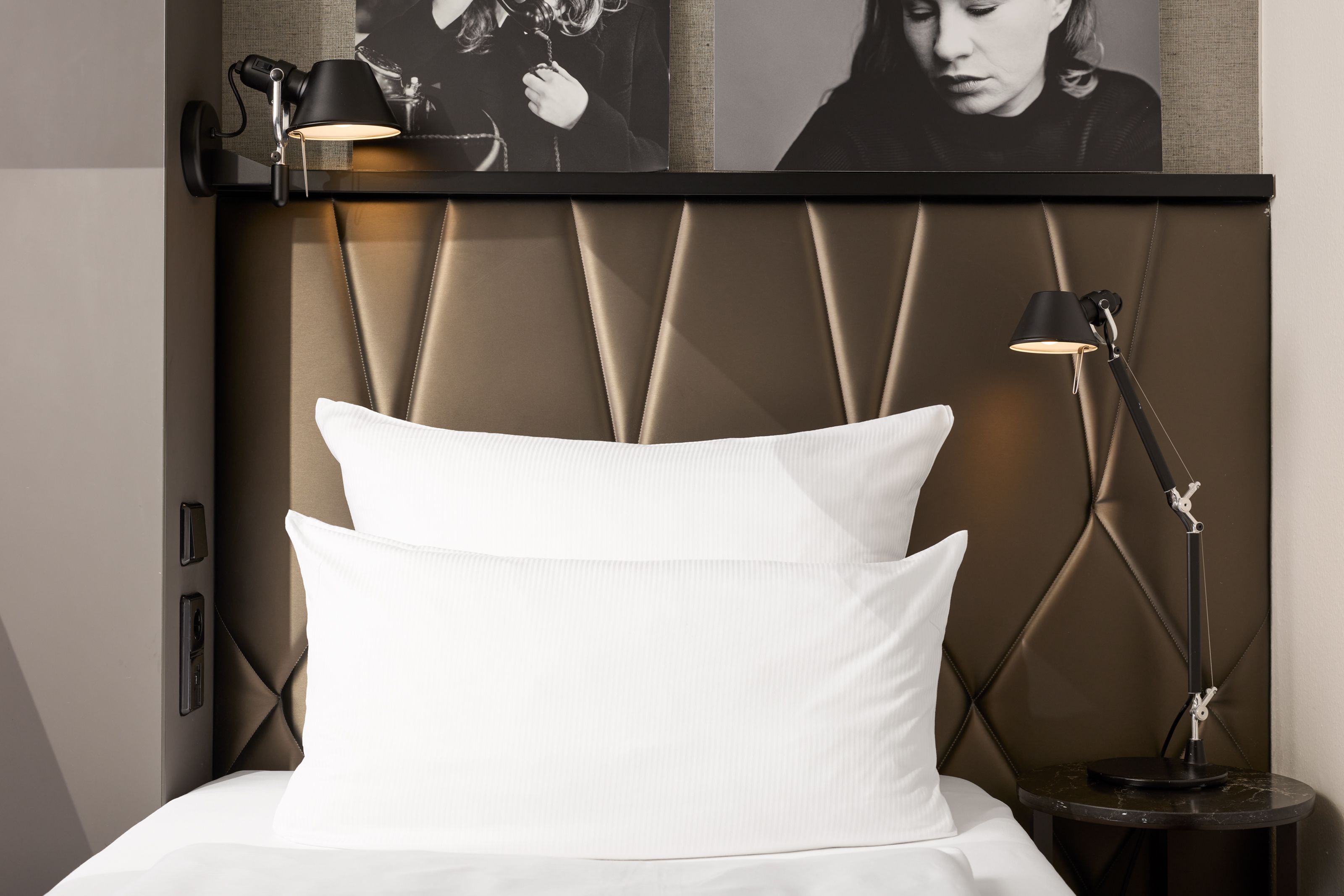 The Cloud One Berlin-Upper West Zeitgemäß eingerichtetes Hotelzimmer mit komfortablem Doppelbett, weißen Kissen, gepolsterter Rückenlehne und stilvollen Nachttischlampen für eine entspannte Atmosphäre.