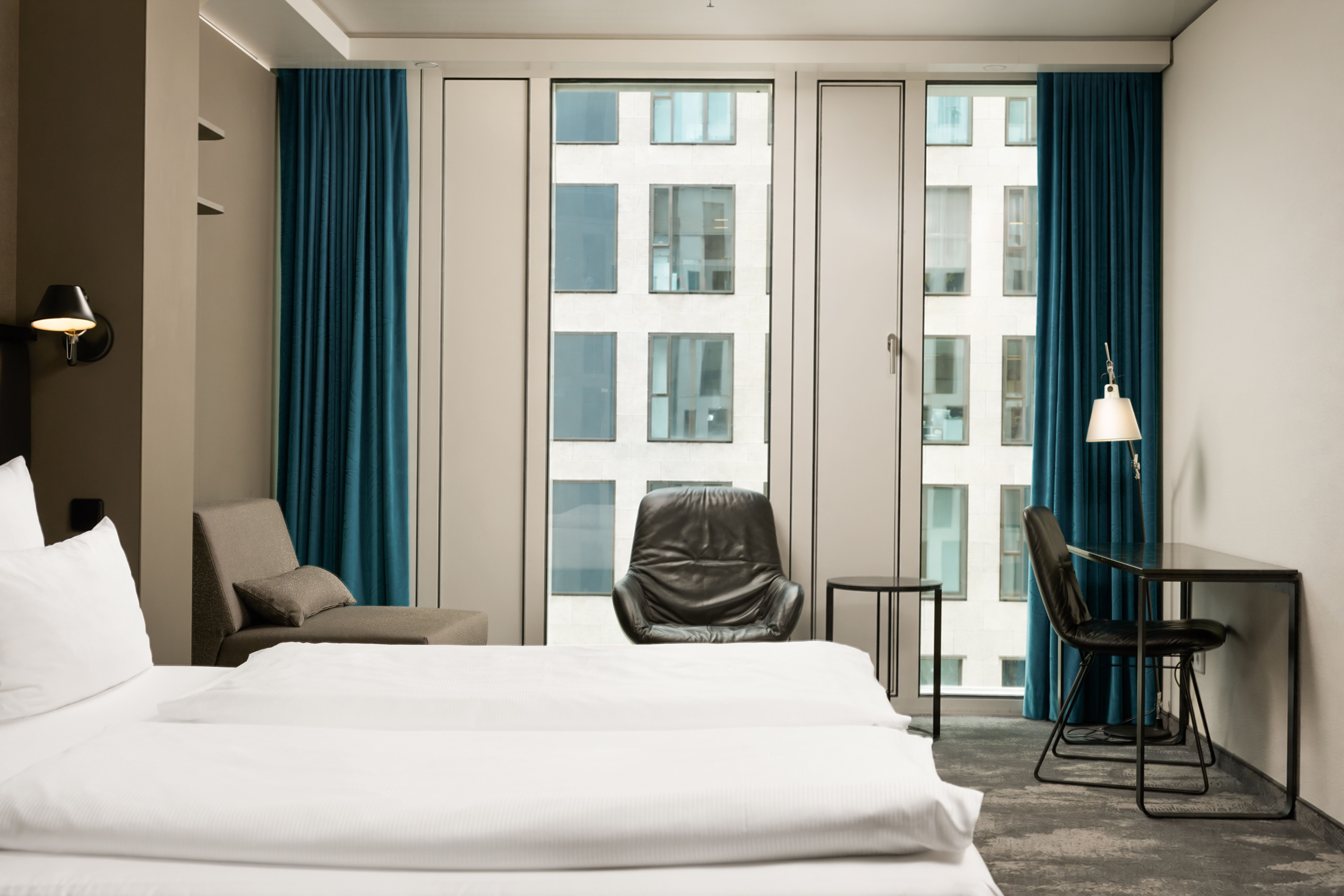 The Cloud One Berlin-Upper West Helles Hotelzimmer mit zwei weißen Betten, einem bequemen Sessel vor großen Fenstern und einem kleinen Arbeitsplatz mit Stuhl, ideal für entspannte oder produktive Momente während des Aufenthalts. The Cloud One Berlin-Upper West Helles Hotelzimmer mit zwei weißen Betten, einem bequemen Sessel vor großen Fenstern und einem kleinen Arbeitsplatz mit Stuhl, ideal für entspannte oder produktive Momente während des Aufenthalts.