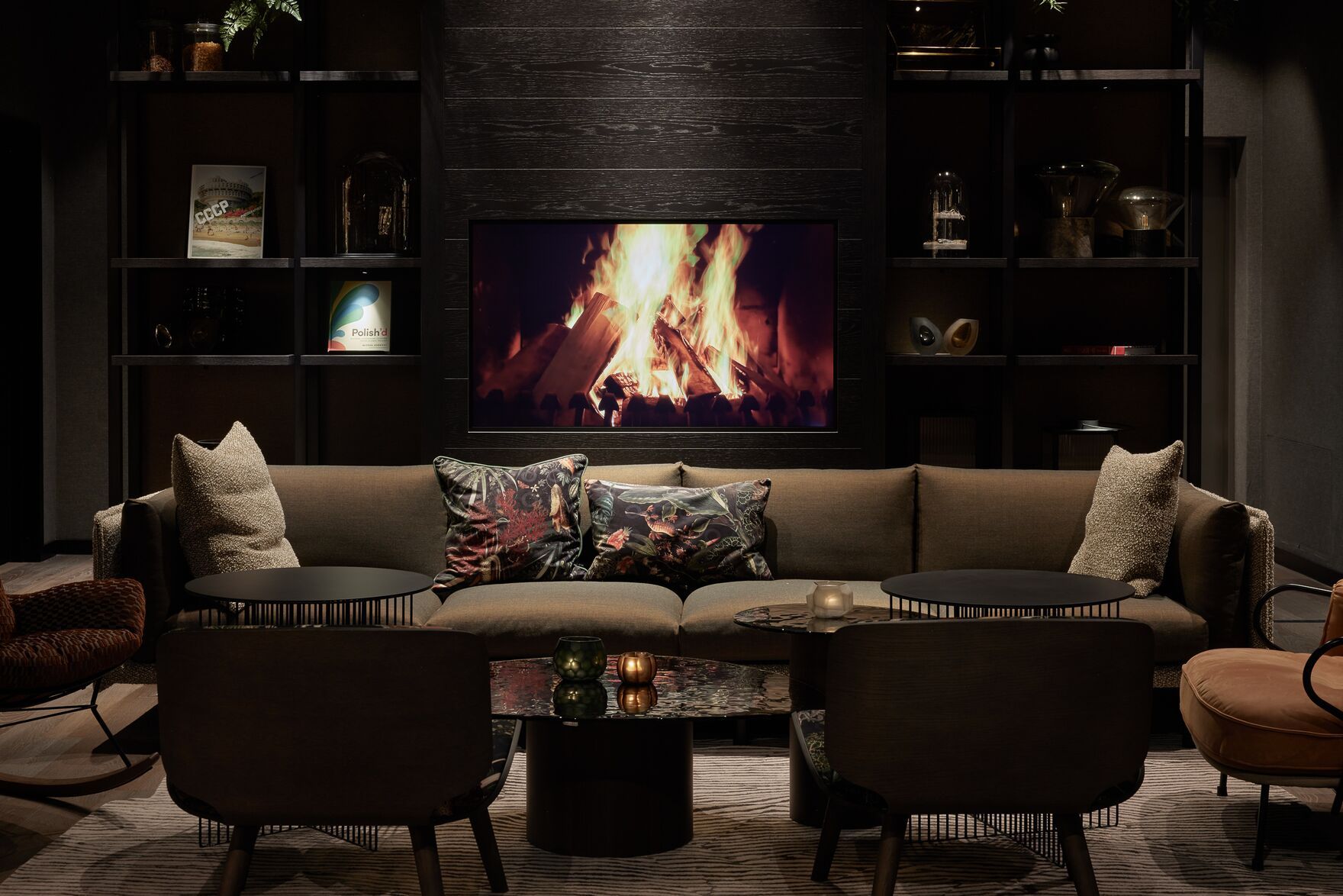 Designhotel Danzig The Cloud One Lounge mit großem Sofa und mehreren Sesseln vor einem Fernseher mit Feuermotiv