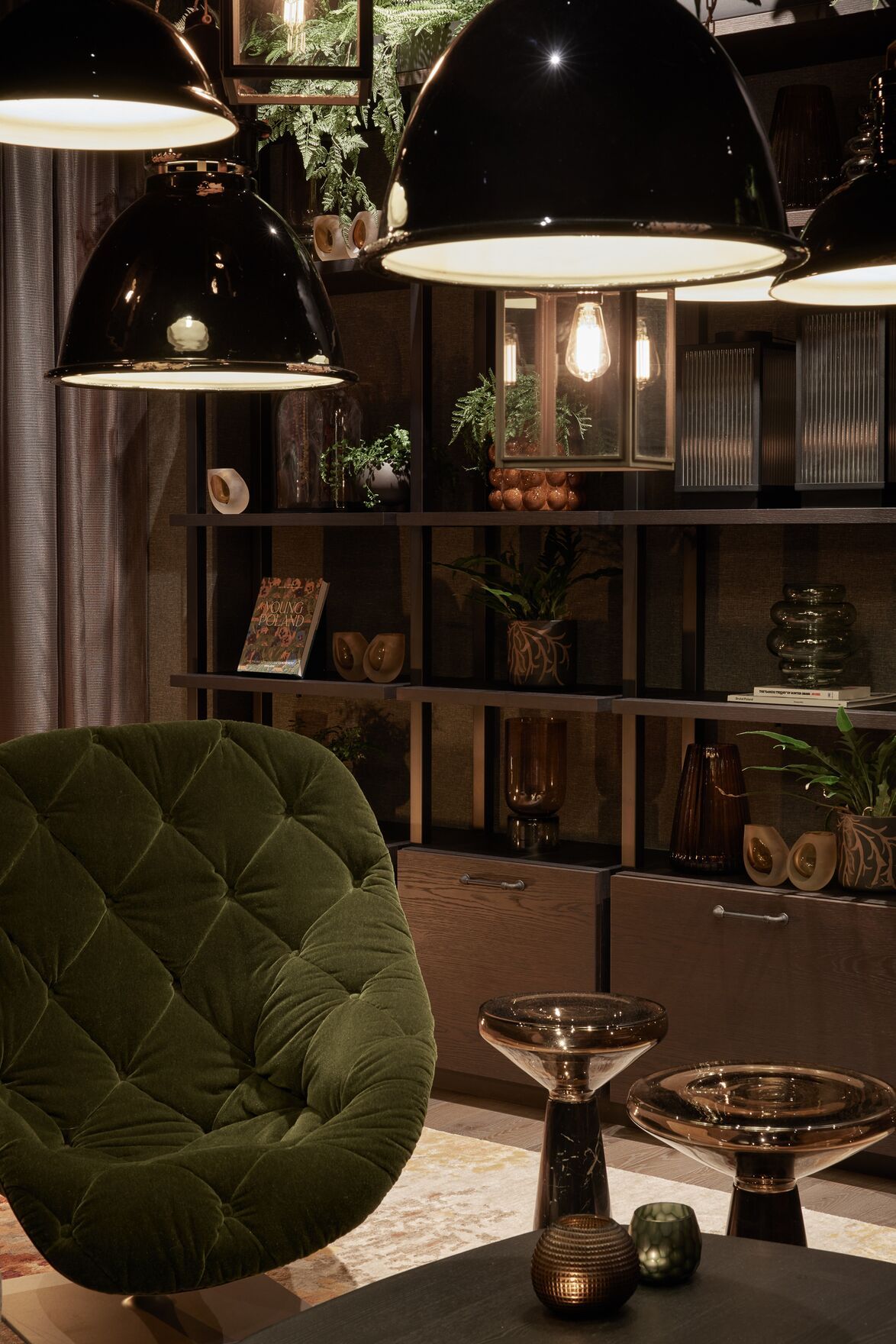 Designhotel Danzig The Cloud One Lounge mit Sessel in dunkelgrün vor offenem Regal