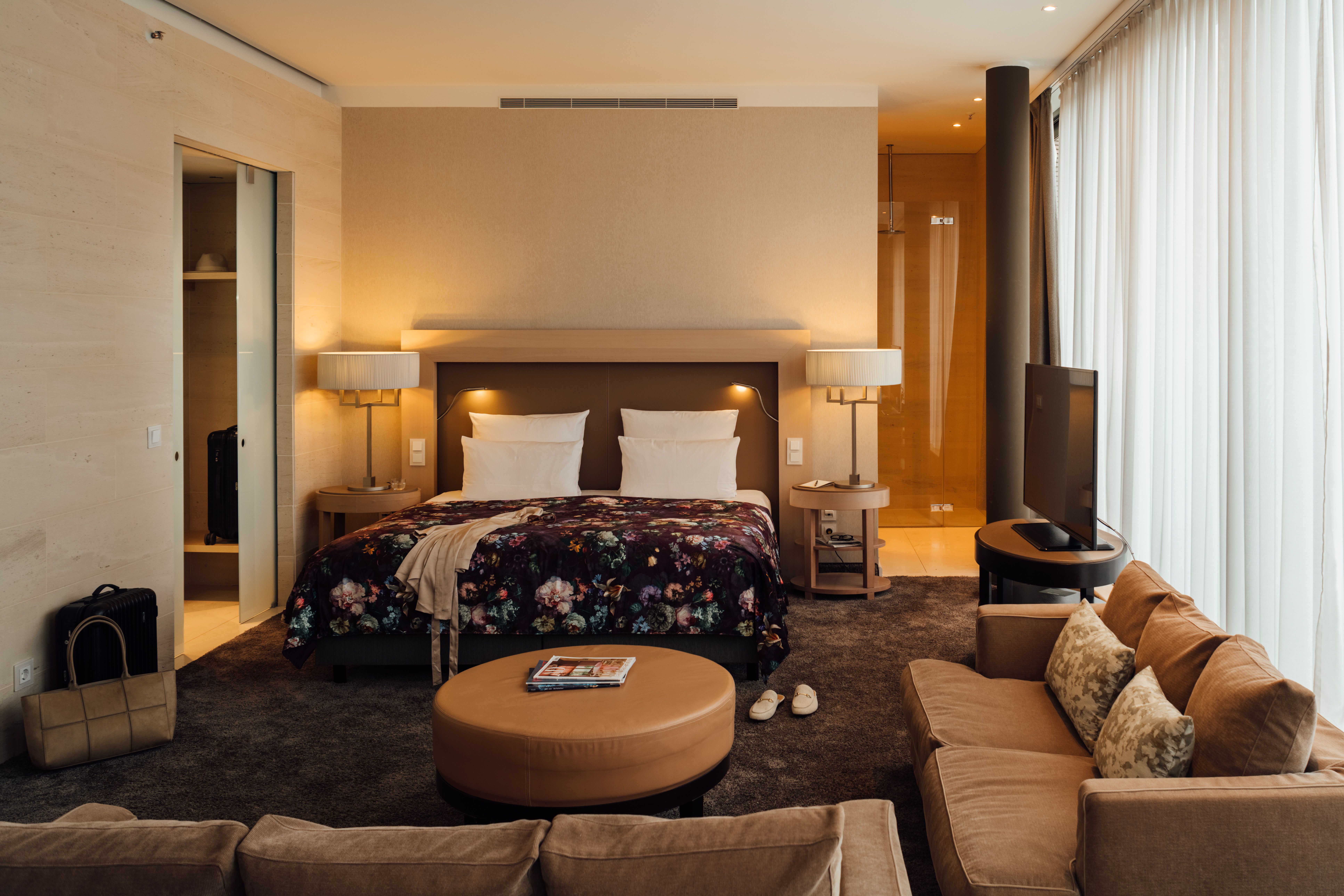 Geschmackvoll eingerichtetes Hotelzimmer mit großem Doppelbett, gemütlichem Sitzbereich, warmem Licht und moderner Ausstattung für erholsamen Aufenthalt.