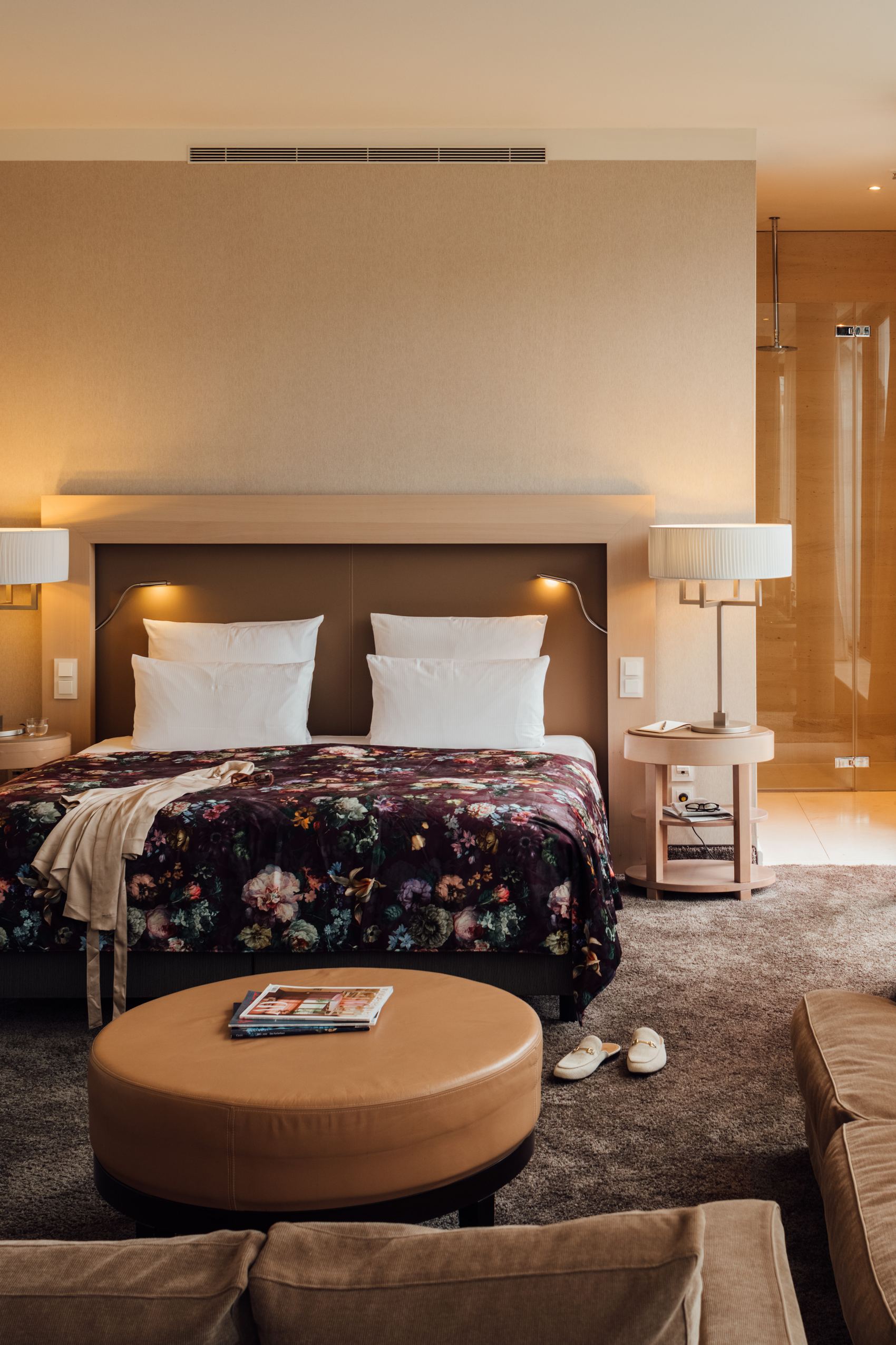 Modern eingerichtetes Hotelzimmer mit großem Doppelbett, gemütlichem Sofa, warmem Licht und Zugang zu einem Balkon mit Außenblick für entspannte Aufenthalte.