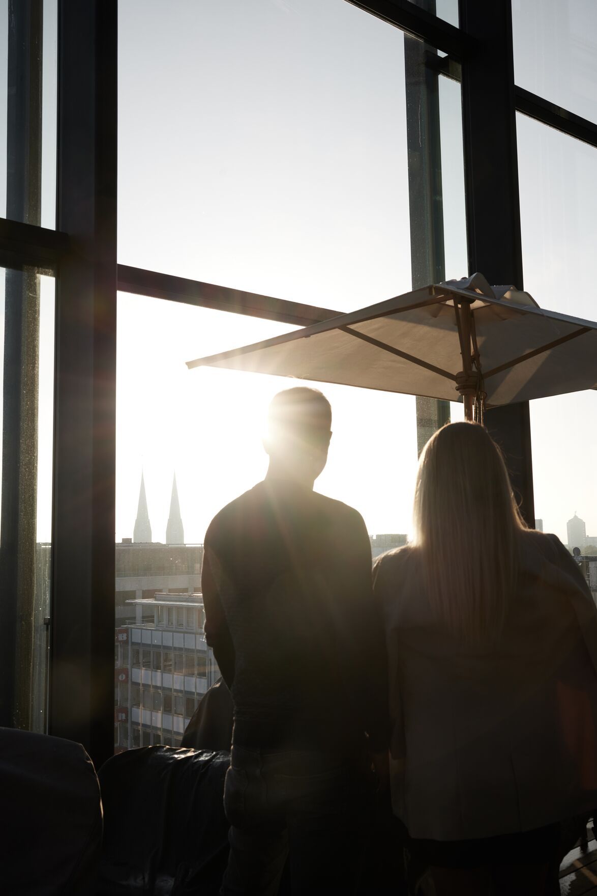 Hotel Düsseldorf KöBogen The Cloud One zwei Personen schauen aus einem hohen Fenster mit Sonne