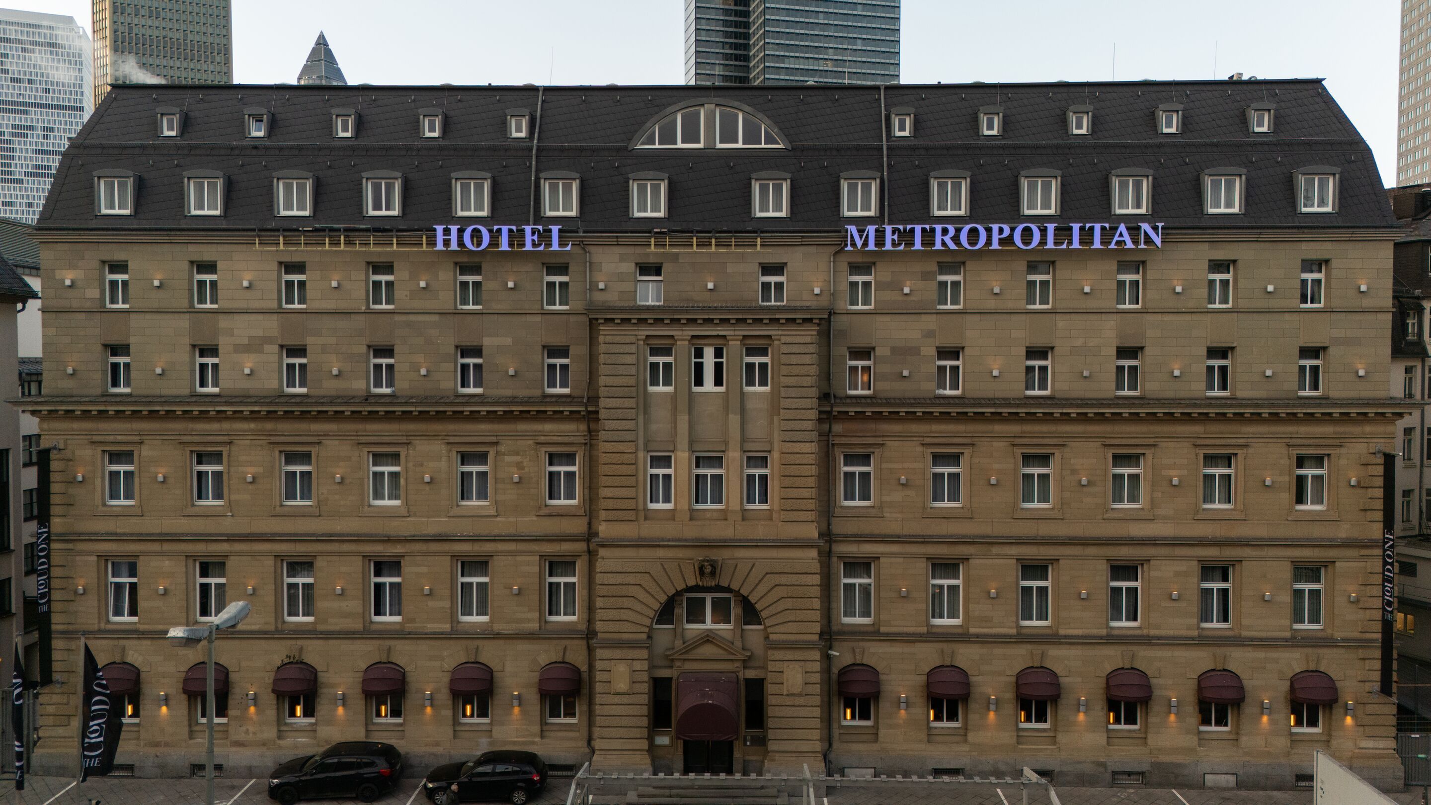 Hotel Frankfurt Metropolitan The Cloud One Außenansicht des Hotels Metropolitan in einem historischen Gebäudekomplex mit zahlreichen Fenstern und dekorativen Elementen, eingebettet zwischen modernen Hochhäusern.