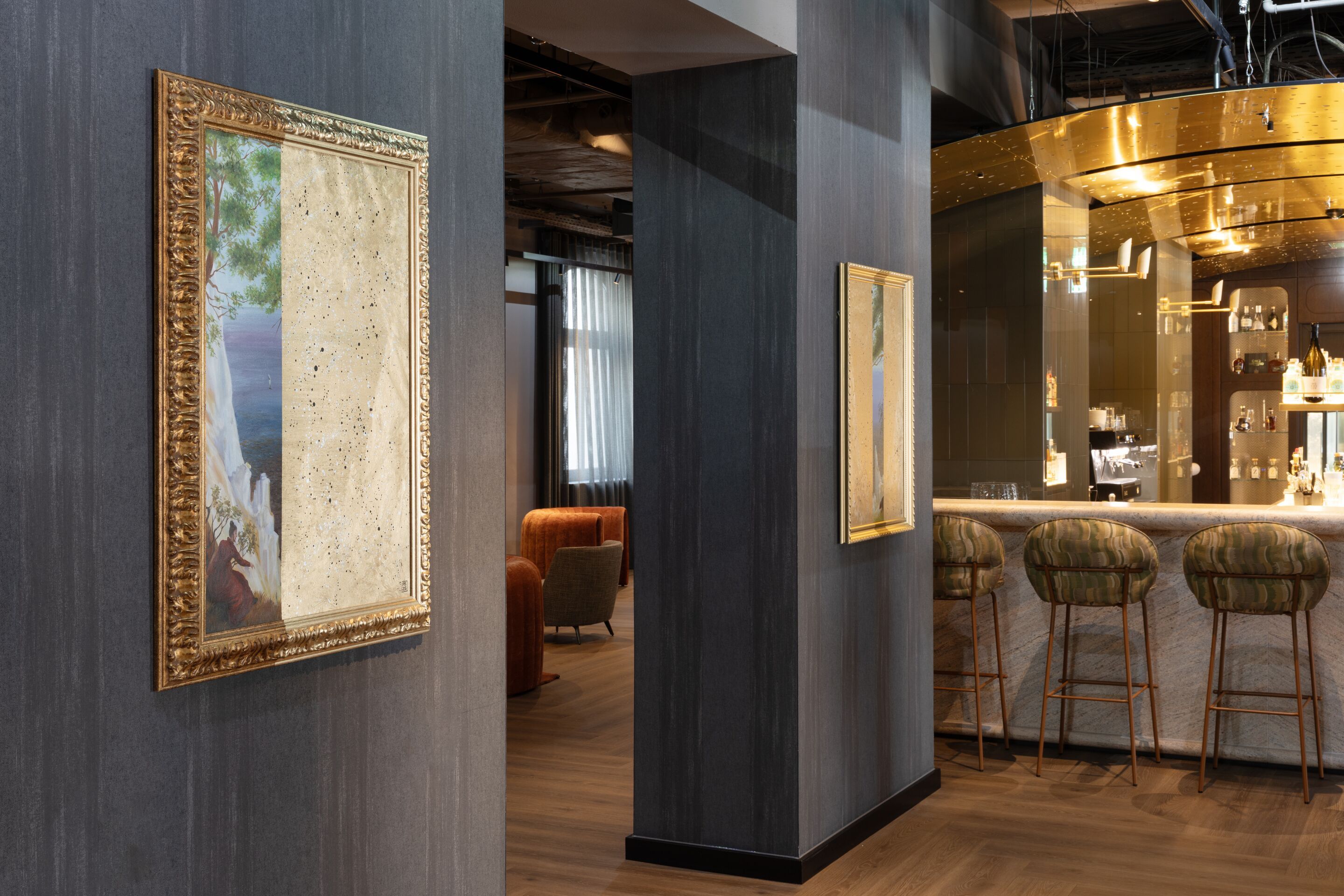Hotel Frankfurt-Metropolitan The Cloud One Bar und Lounge mit eleganter Theke und Barhockern, gemütliche Sitzecke im Hintergrund, stilvolle Wanddekoration mit einem goldgerahmten Spiegel, warme Beleuchtung und dunkle Holzakzente.