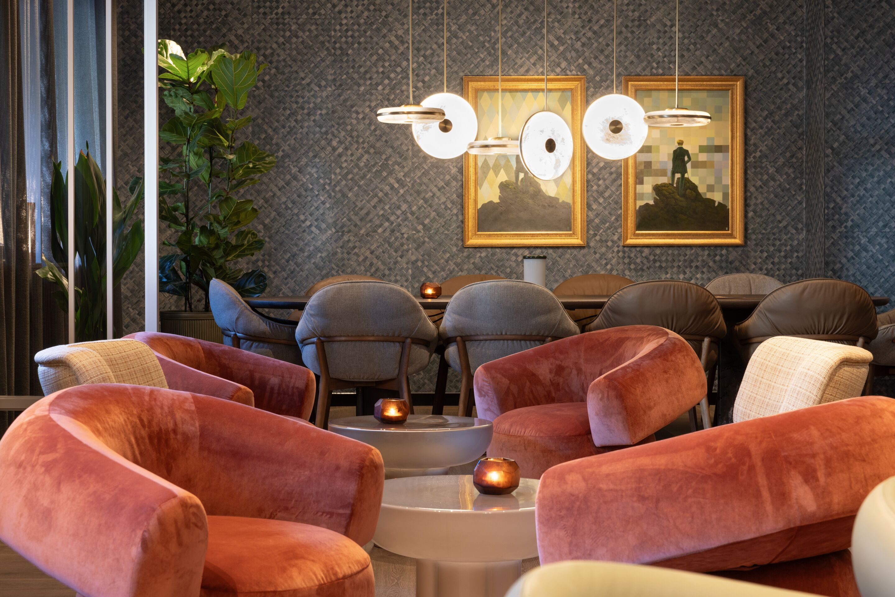 Hotel Frankfurt-Metropolitan The Cloud One Lounge-Bereich mit samtigen, pfirsichfarbenen Sesseln, eleganten grauen Stühlen, modernen Pendelleuchten und stilvollen Wandbildern.