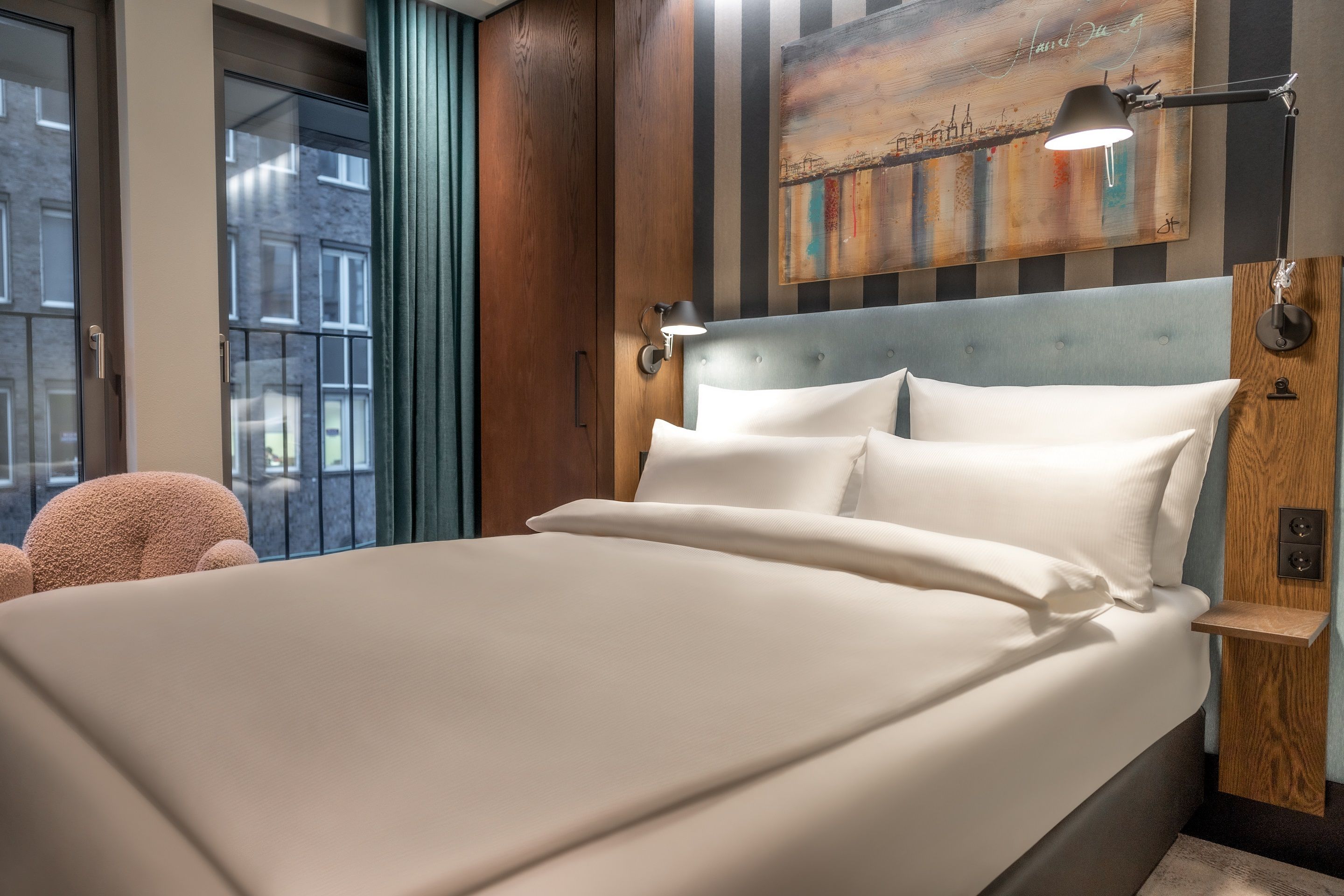 Hotel Hamburg Kontorhaus The Cloud One Zimmer mit Blick auf Doppelbett sowie bodentiefe Fenster und Sessel in rosa