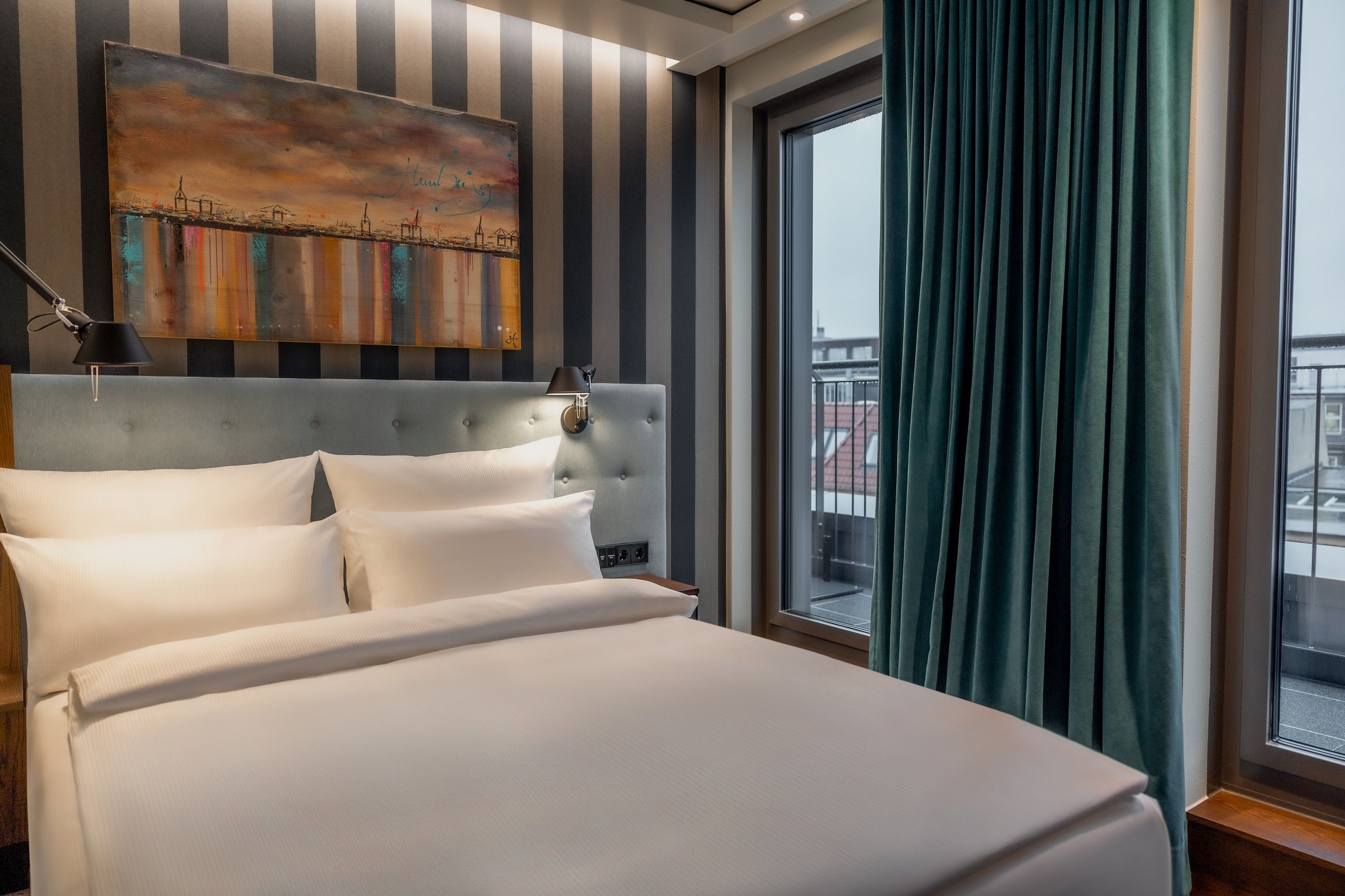 Hotel Hamburg Kontorhaus The Cloud One Zimmer mit großem Doppelbett, Gemälde über dem Bett sowie Balkonzugang