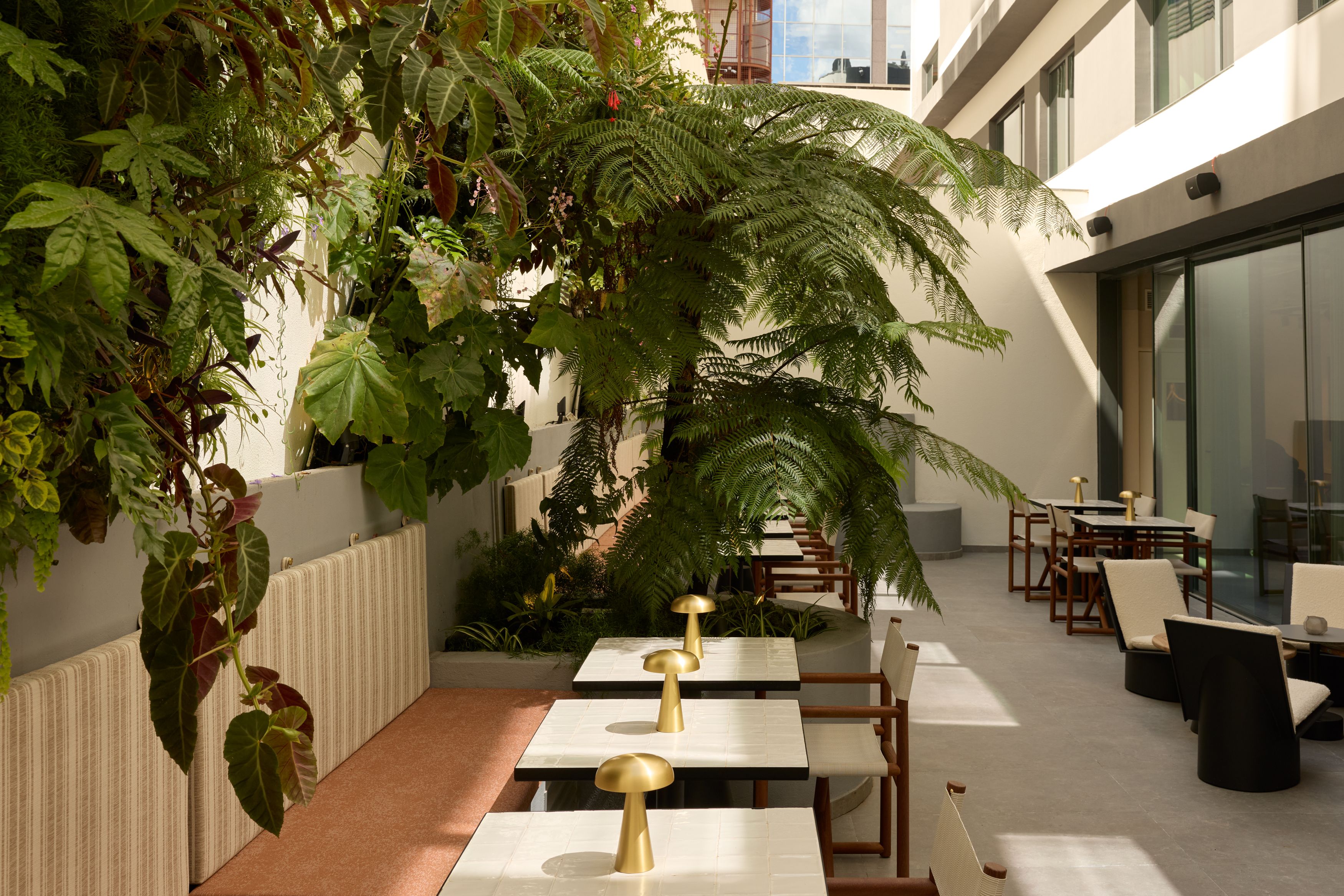 Designhotel Lissabon The Cloud One Außenbereich mit schattigen Sitzplätzen, gedeckten Tischen und üppiger Begrünung, der eine entspannte Atmosphäre für Mahlzeiten oder Pausen bietet.