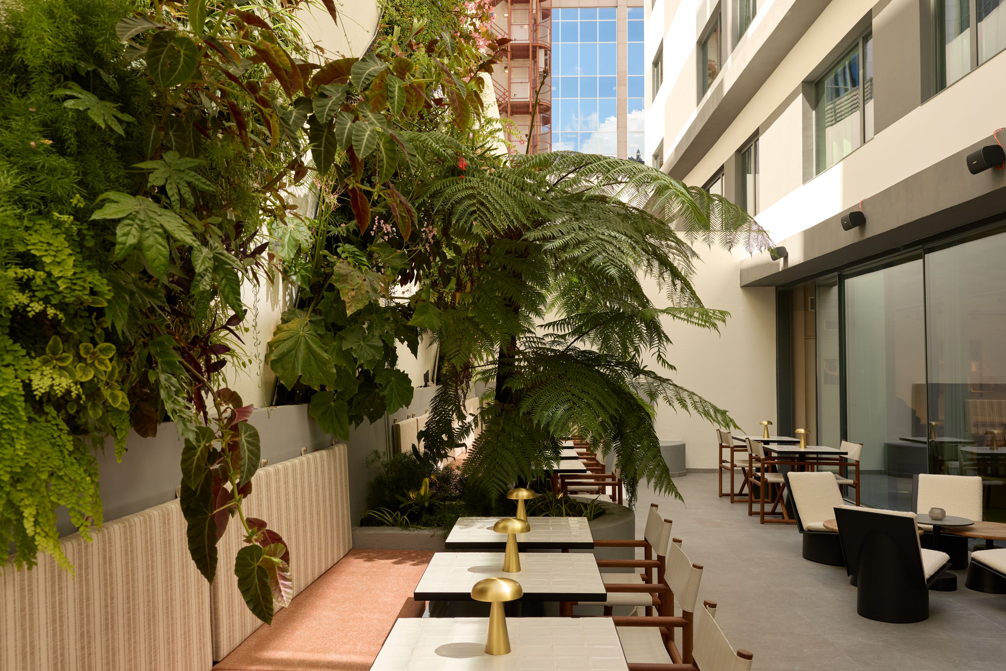 Hotel Lissabon The Cloud One Außenbereich mit Tischen, Stühlen und üppiger Begrünung, der eine entspannte Atmosphäre zum Essen und Verweilen bietet.