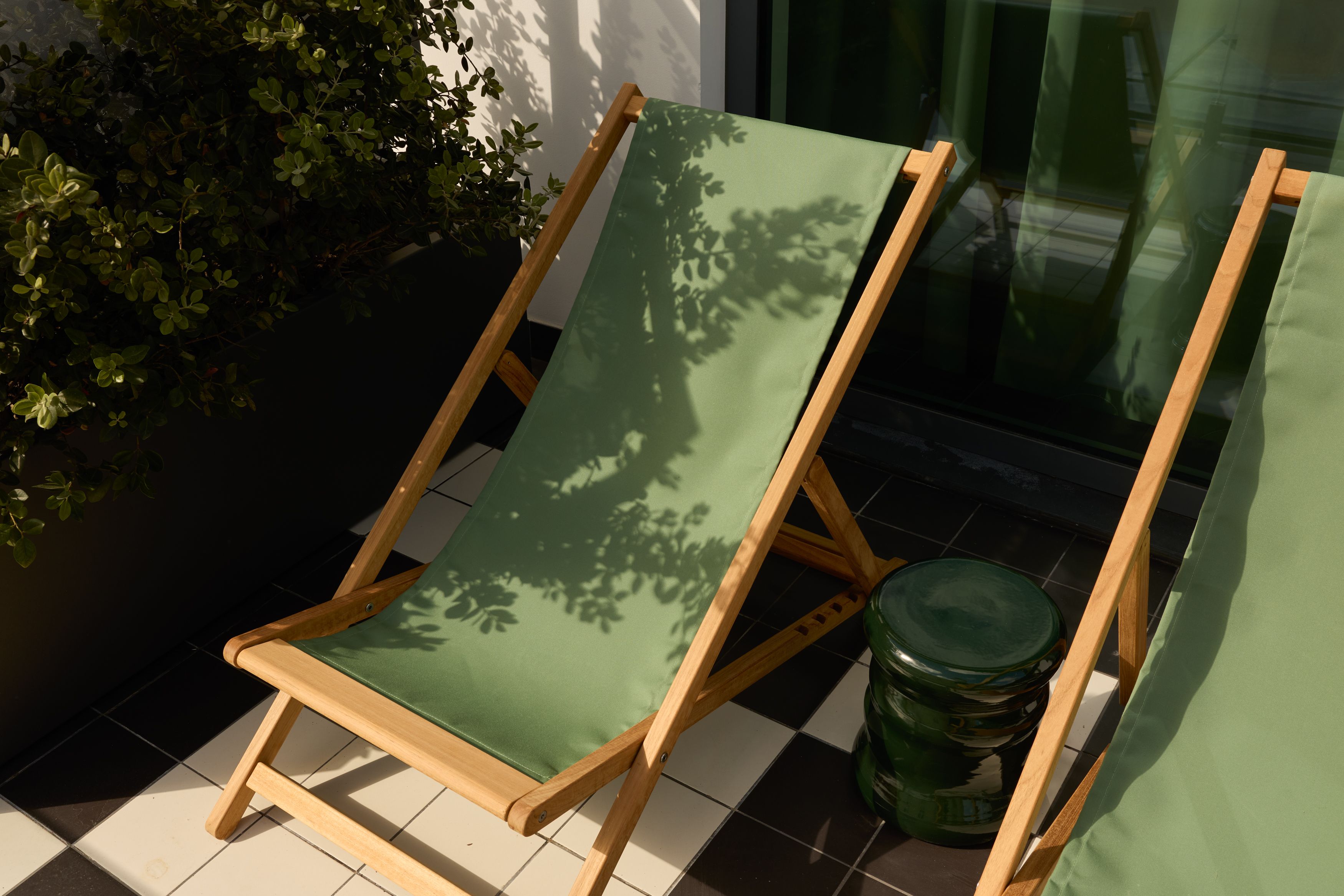 Hotel Lissabon The Cloud One zwei grüne Liegestühle auf einem sonnigen Balkon mit Pflanze im Hintergrund, ideal zum Entspannen und Genießen der warmen Atmosphäre.
