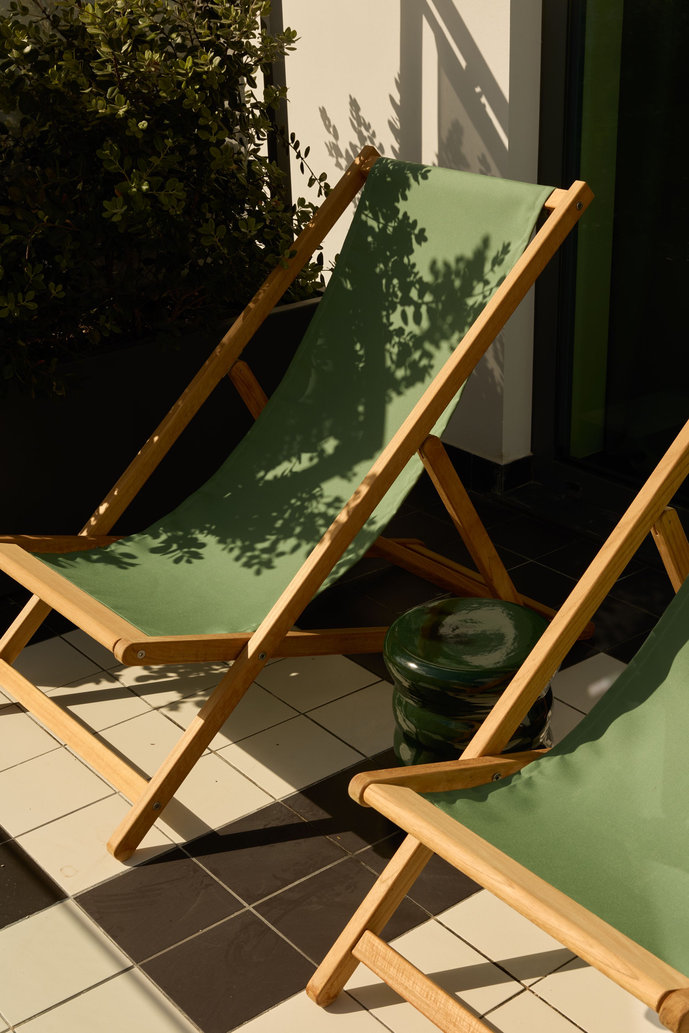 Designhotel Lissabon The Cloud One zwei grüne Liegestühle aus Holz stehen auf einer sonnigen Terrasse, ideal zum Entspannen im Freien.