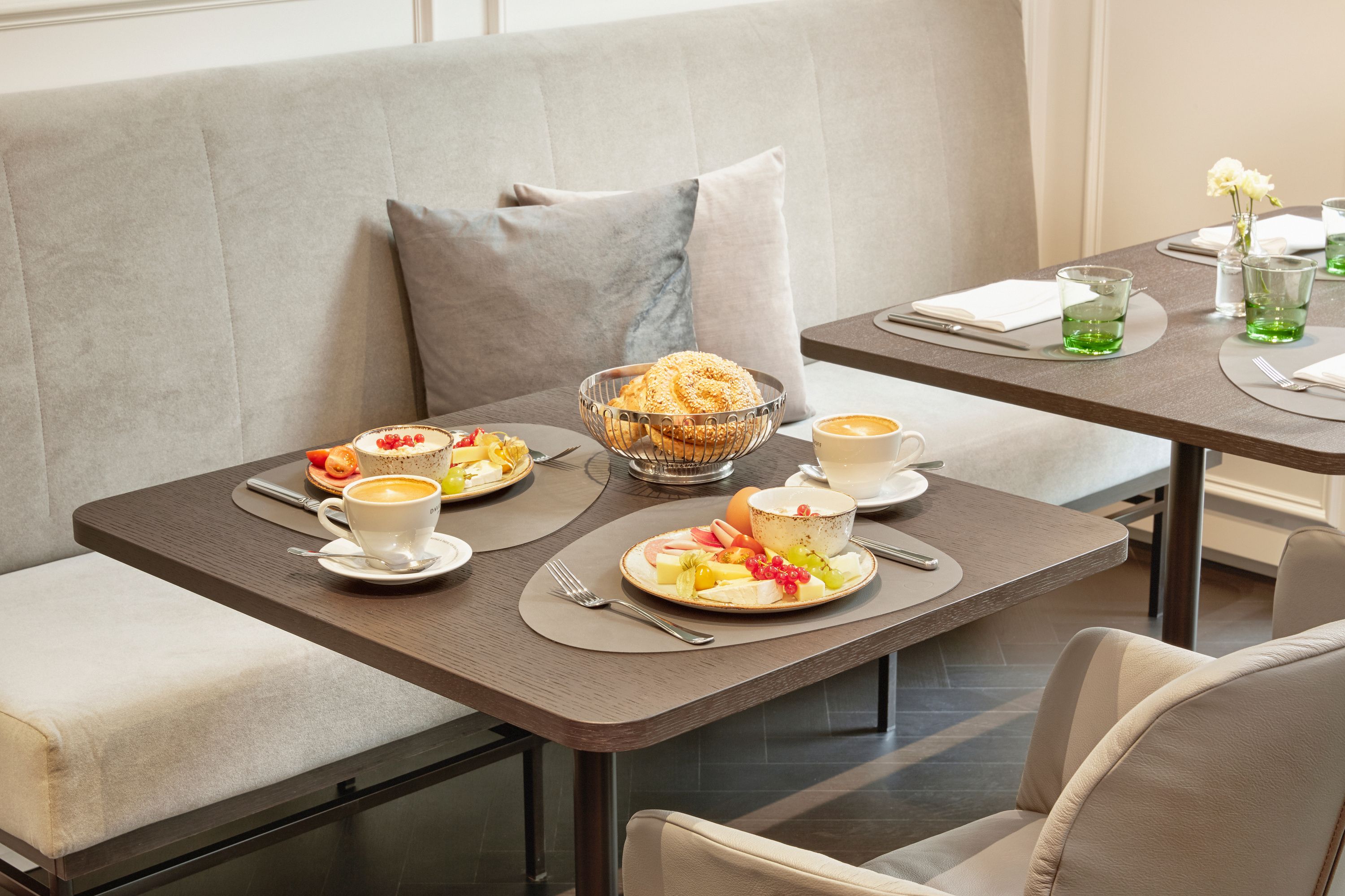 Gemütlicher Frühstückstisch mit gedeckten Tellern, Kaffee, frischem Gebäck und ansprechender Sitzbank, ideal für einen entspannten Start in den Tag.