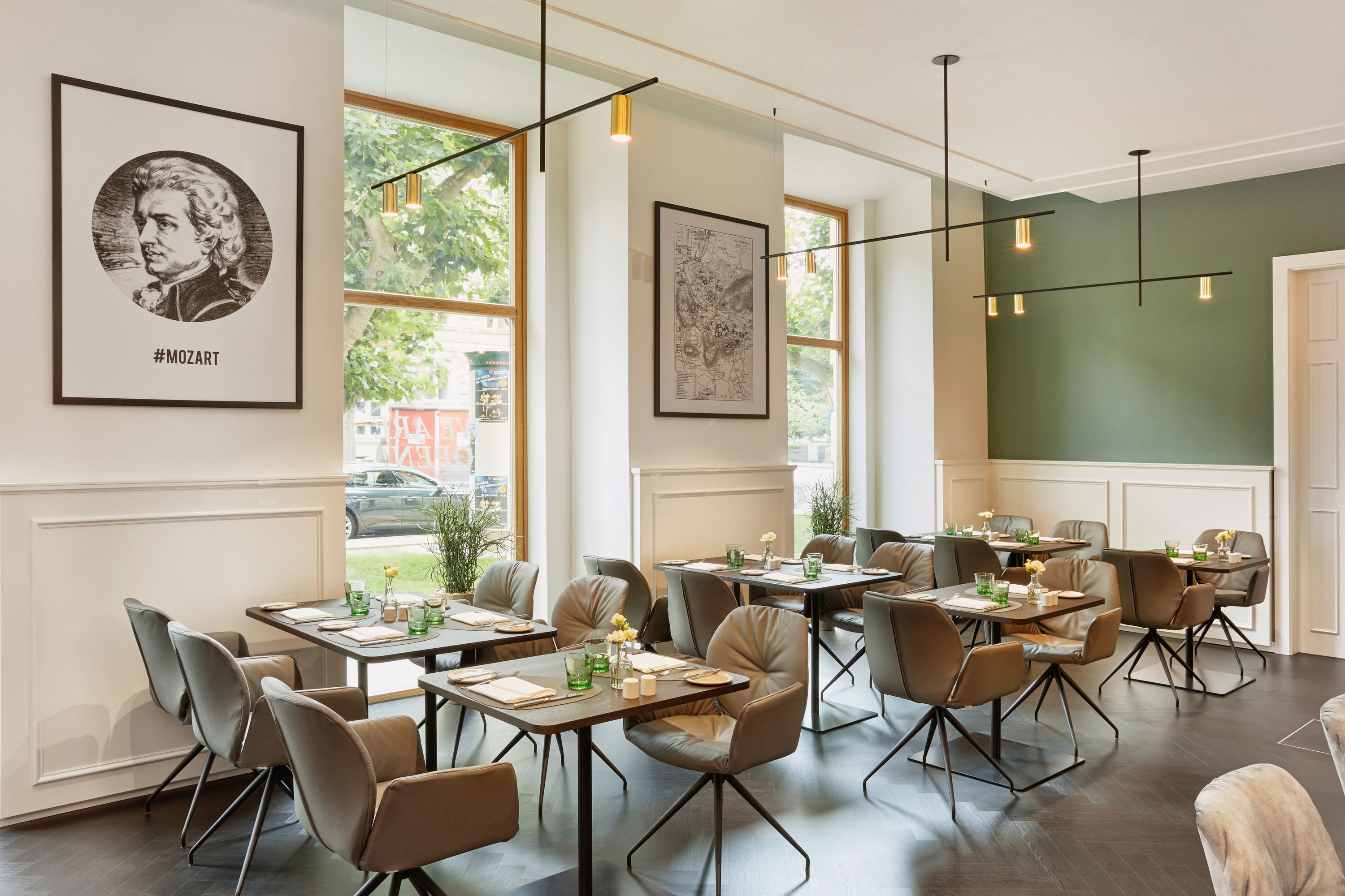 Modernes, helles Restaurant mit großen Fenstern, gemütlichen Sesseln und elegant gedeckten Tischen. Warme Beleuchtung und stilvolle Wanddekoration schaffen eine einladende Atmosphäre für entspannte Mahlzeiten.