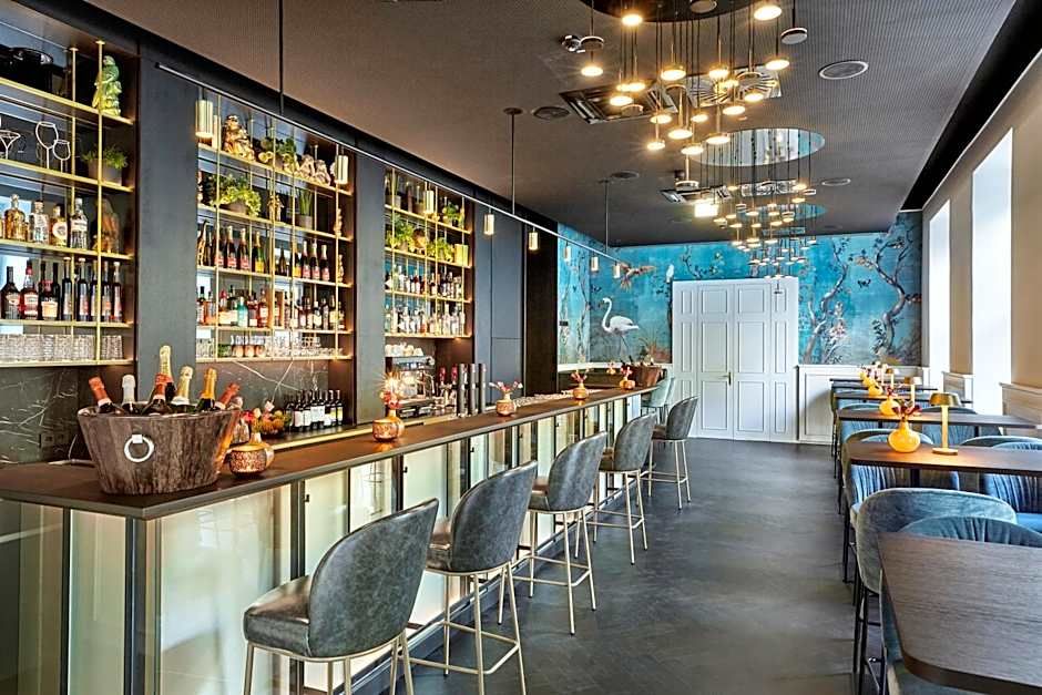 Moderne Hotelbar mit eleganten Barhockern, gut bestücktem Regal mit Spirituosen, stimmungsvoller Beleuchtung und stilvollem Wandbild. Gemütliche Sitzbereiche laden zum Verweilen ein.