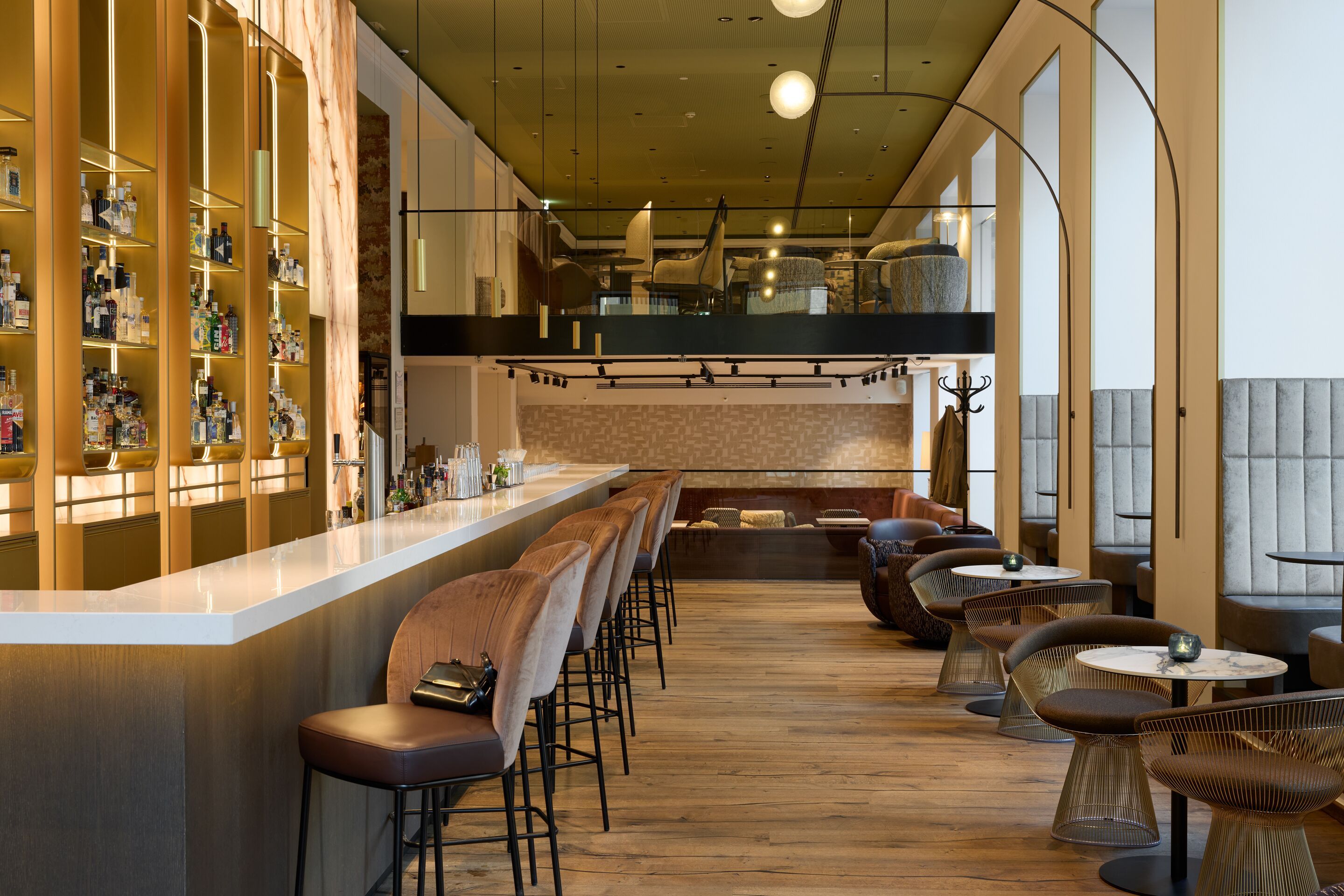 Elegante Hotelbar mit modernem Design, gepolsterten Barhockern, gemütlichen Sitzbereichen und warmem, einladendem Ambiente für entspannte Abende oder gesellige Treffen.