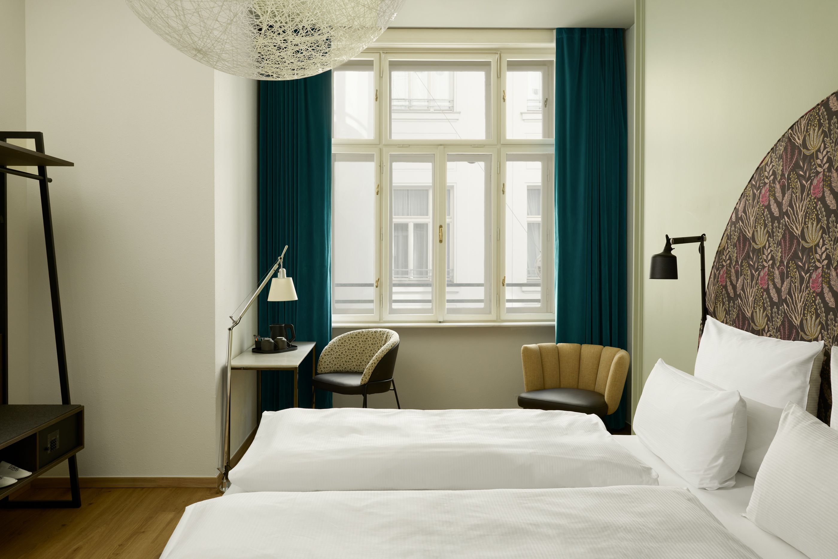 Hotel The Cloud One Wien-Staatsoper Helles Hotelzimmer mit zwei Einzelbetten, großem Fenster, dunkelgrünen Vorhängen und stilvollen Sitzgelegenheiten für entspanntes Wohlfühlen.