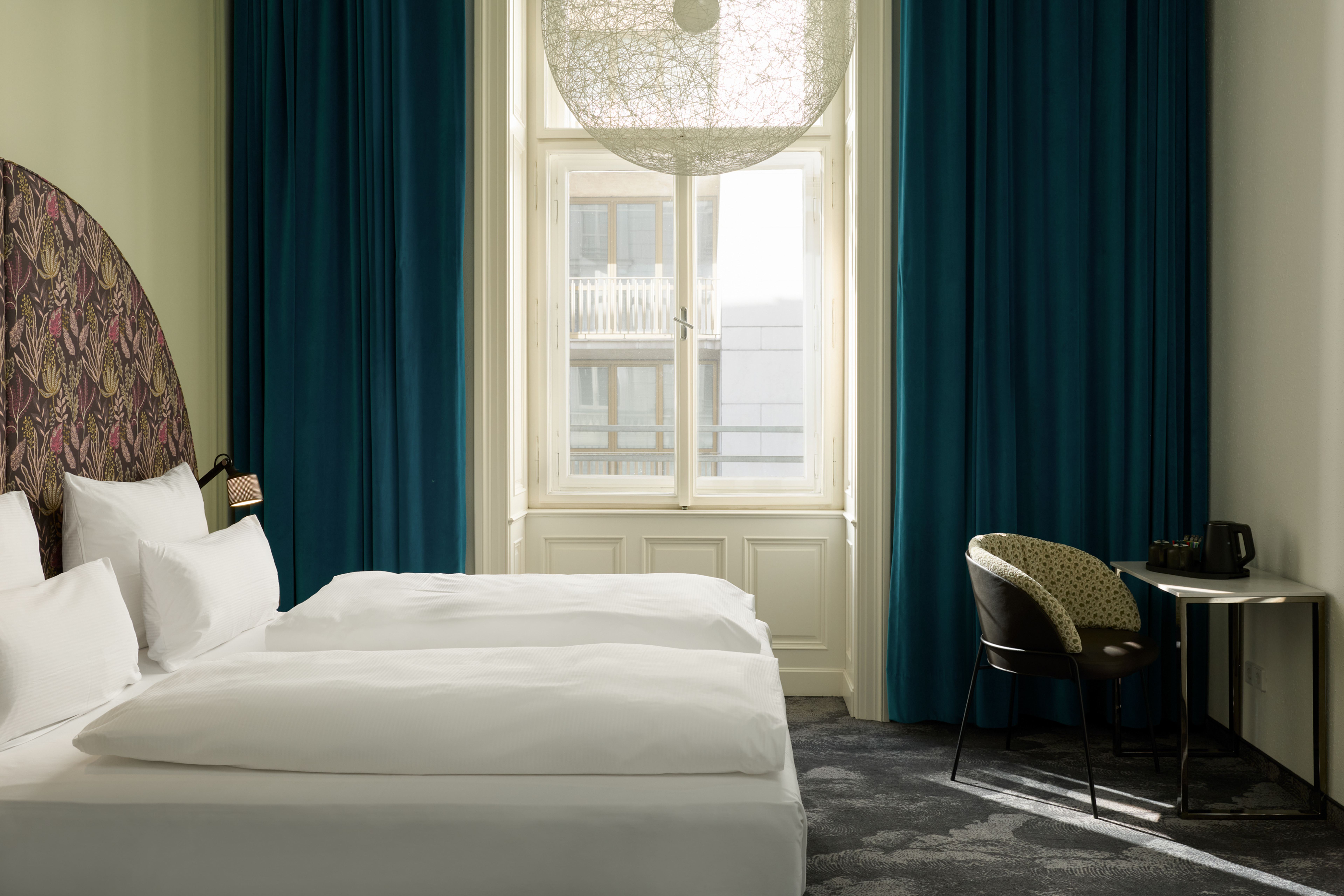 Hotel The Cloud One Wien-Staatsoper Helles Hotelzimmer mit zwei modernen Einzelbetten, großem Fenster mit Tageslicht, blauem Vorhang und stilvollem Arbeitsplatz mit Stuhl. Atmosphäre wirkt ruhig und einladend. Hotel The Cloud One Wien-Staatsoper Helles Hotelzimmer mit zwei modernen Einzelbetten, großem Fenster mit Tageslicht, blauem Vorhang und stilvollem Arbeitsplatz mit Stuhl. Atmosphäre wirkt ruhig und einladend.