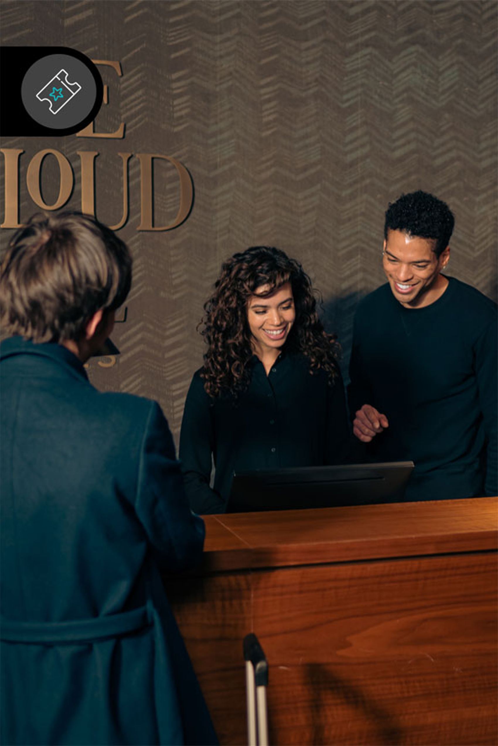 Zwei freundliche Rezeptionisten begrüßen einen Gast an der Hotelrezeption, bereiten den Check-in vor und sorgen für einen angenehmen Empfang.