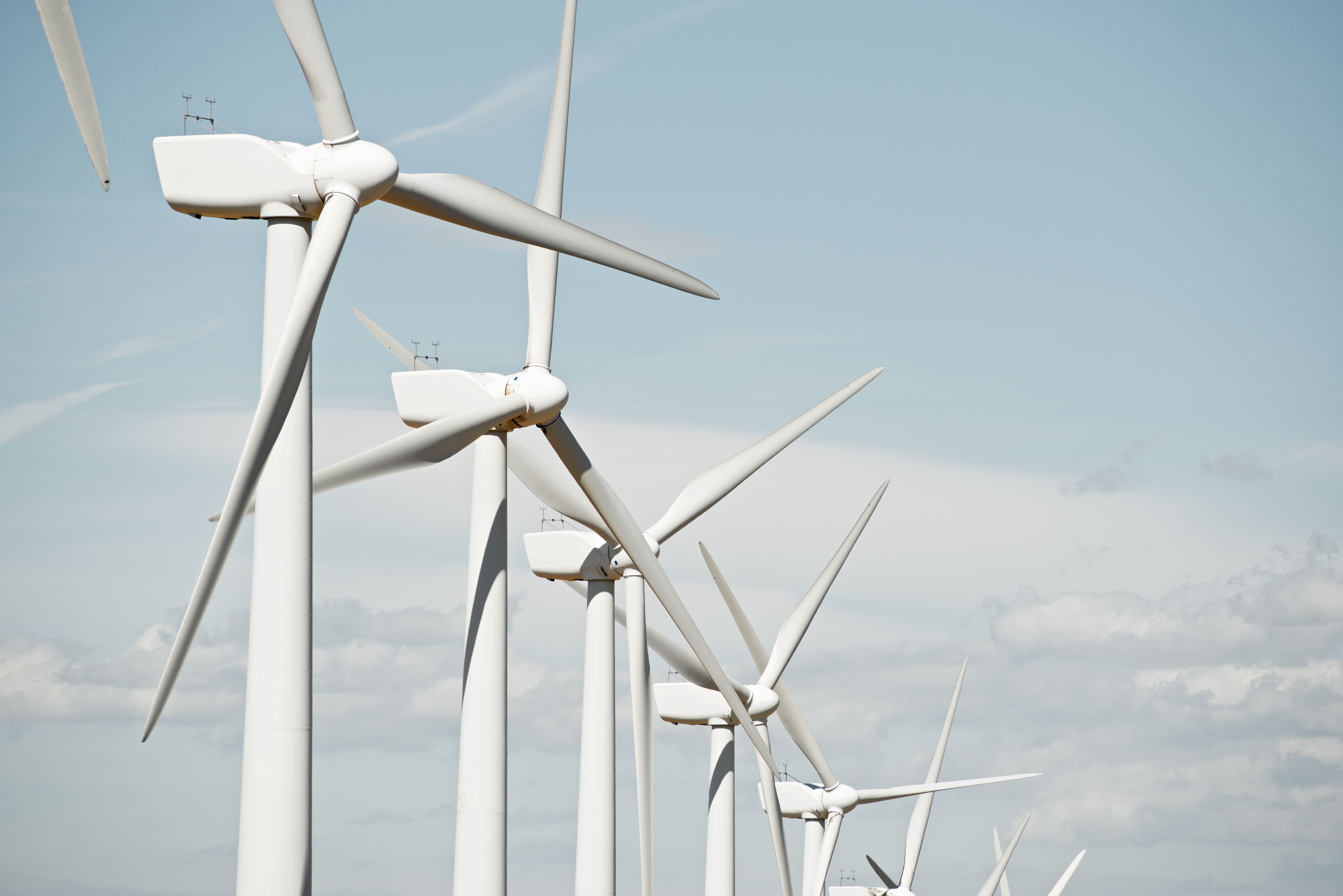 Reihe moderner Windräder unter blauem Himmel, die nachhaltige Energie durch Windkraft erzeugen.