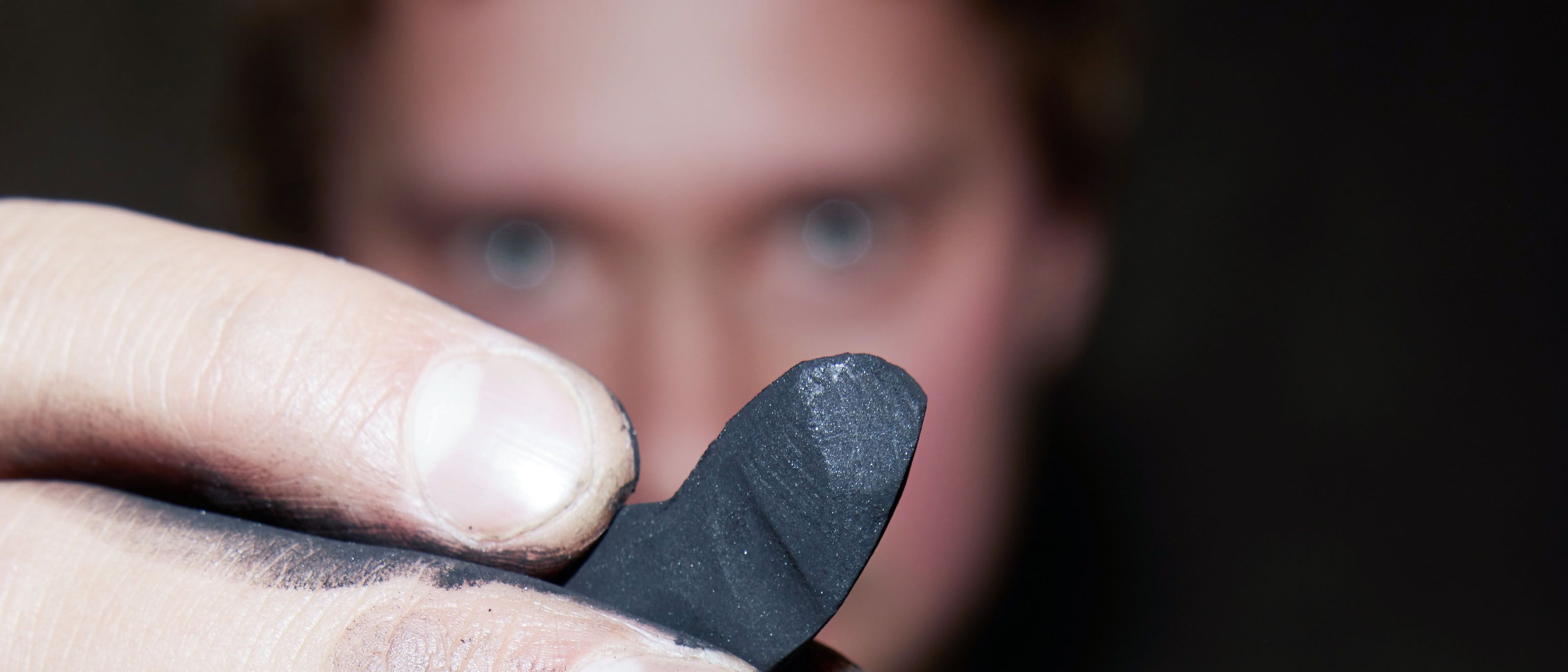 designhotel Gdansk The Cloud One artist Vasyl Savchenko holds a piece of natural charcoal up to the camera.