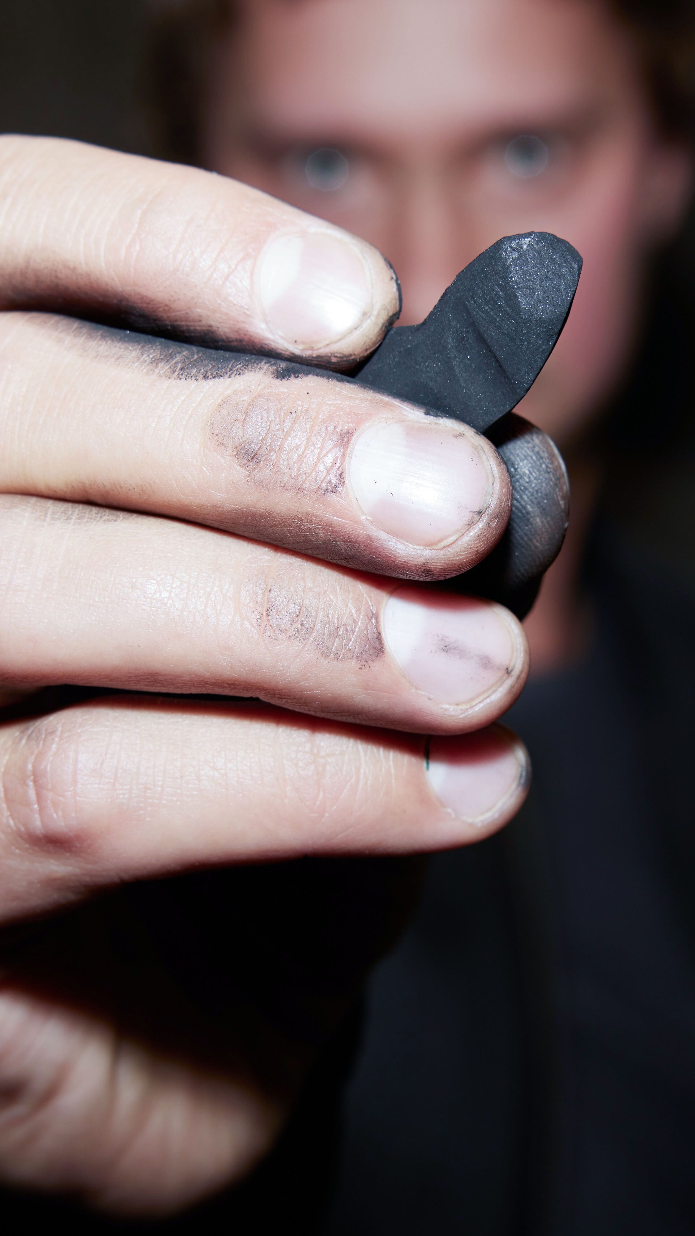 designhotel Gdansk The Cloud One artist Vasyl Savchenko holds a piece of natural charcoal up to the camera.