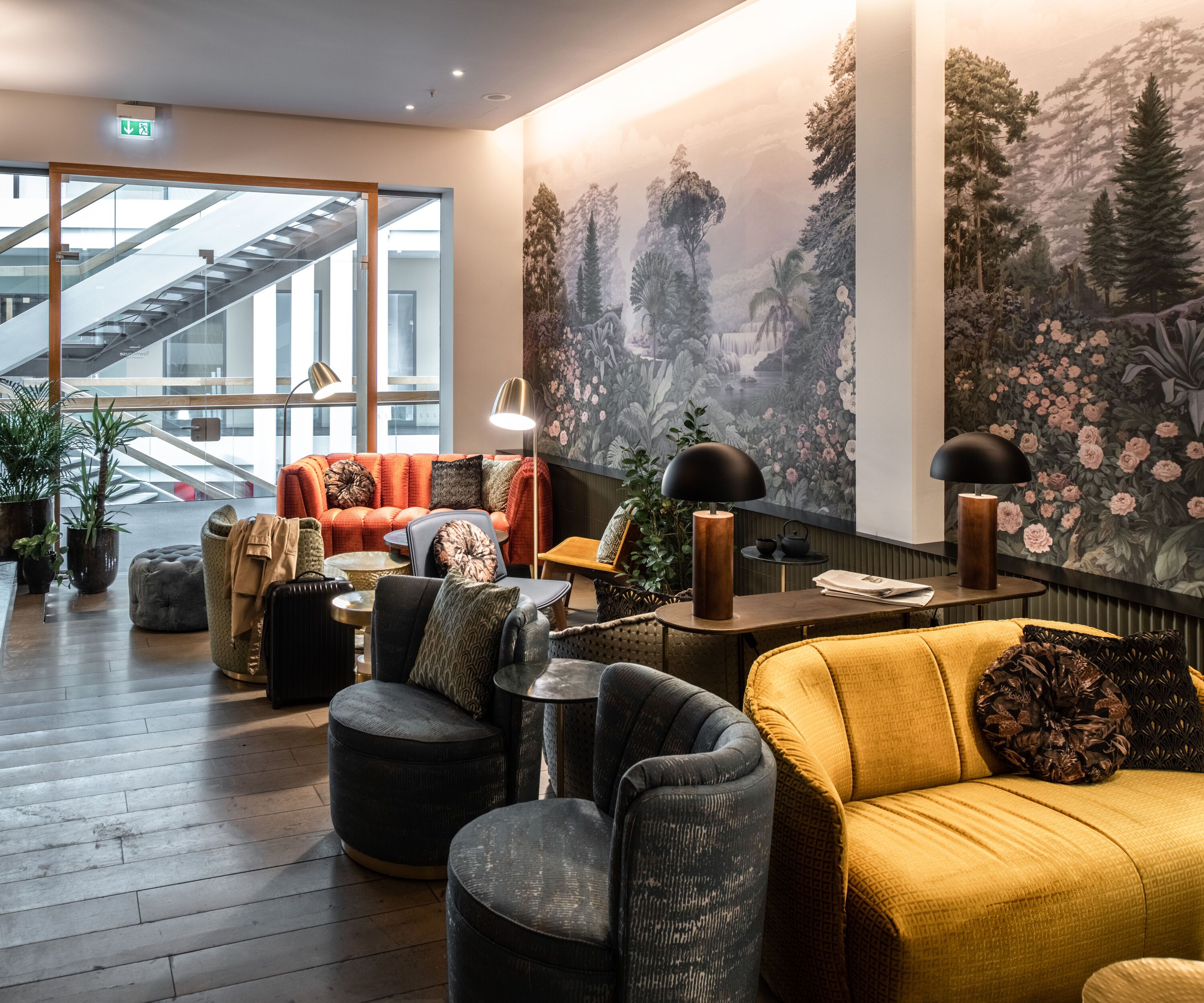 Gemütlicher Lounge-Bereich mit bequemen Sesseln und Sofas in warmen Farben, stimmungsvolle Beleuchtung und Wandbilder mit Naturmotiven, ideal zum Entspannen und Verweilen.