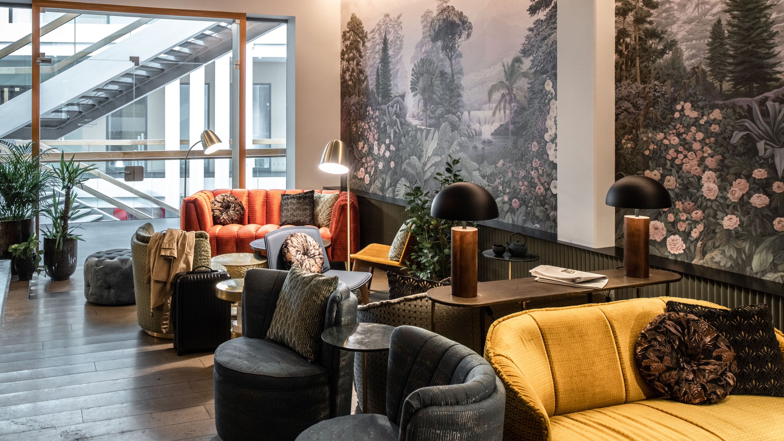 Gemütlicher Lounge-Bereich mit bequemen Sesseln und Sofas in warmen Farben, stimmungsvolle Beleuchtung und Wandbilder mit Naturmotiven, ideal zum Entspannen und Verweilen.