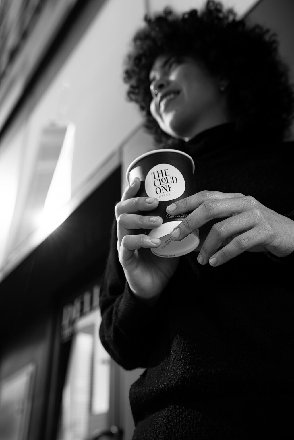 Frau hält einen Kaffe vom The Cloud One Deli