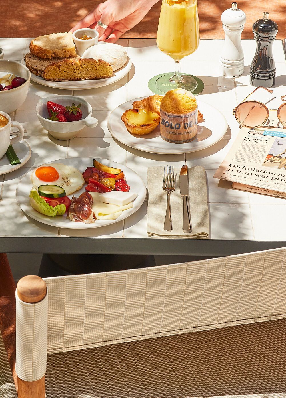 Frühstückstisch mit frischem Gebäck, Kaffee, Müsli, Obst, herzhaften kleinen Speisen und einem Orangensaft in sonniger, gemütlicher Atmosphäre.