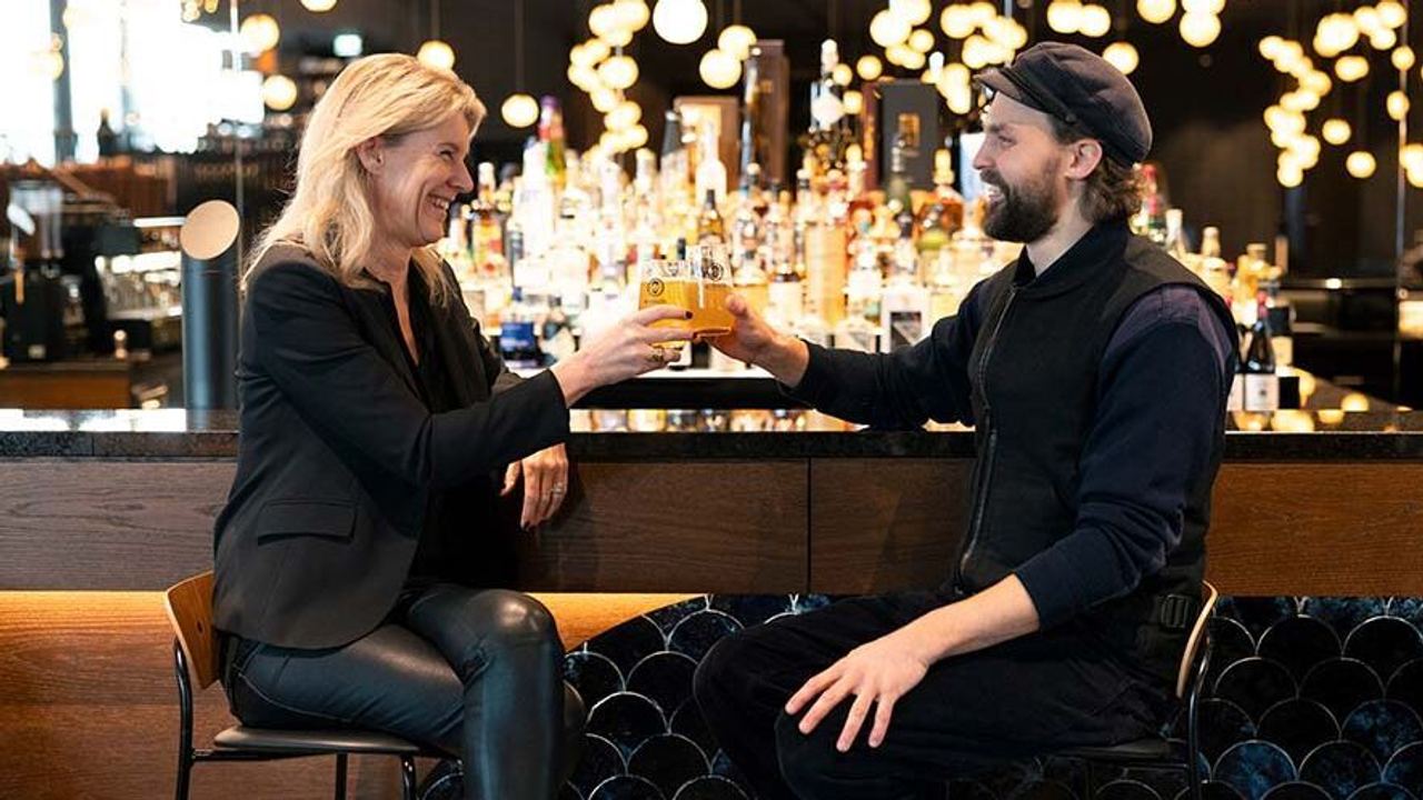 Zwei Gäste stoßen lächelnd mit Getränken an einer eleganten Hotelbar an