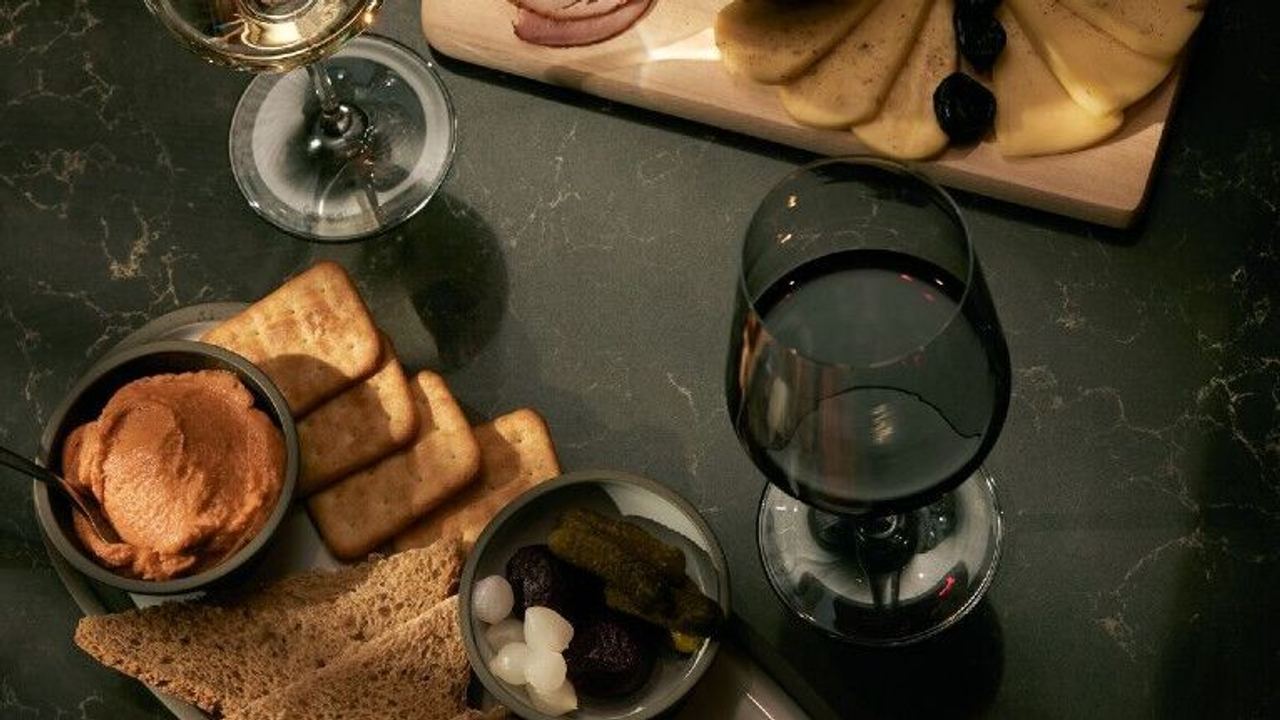 Hotel Danzig The Cloud One Blick von oben auf einen Tisch mit Snacks sowie eine Wurst- und Käseplatte und zwei Weißweingläser