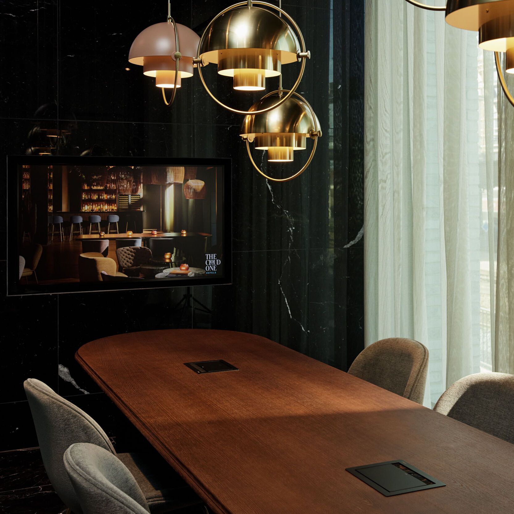 Motel One Konferenzraum mit langem Holztisch, bequemen Stühlen und großen Fenstern, die Tageslicht hereinlassen. Stilvolle goldene Hängeleuchten pendeln von der Decke.