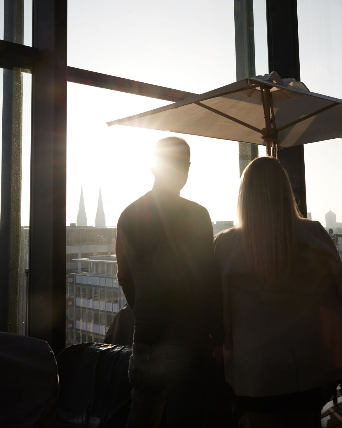 Hotel Düsseldorf KöBogen The Cloud One zwei Personen schauen aus einem hohen Fenster mit Sonne
