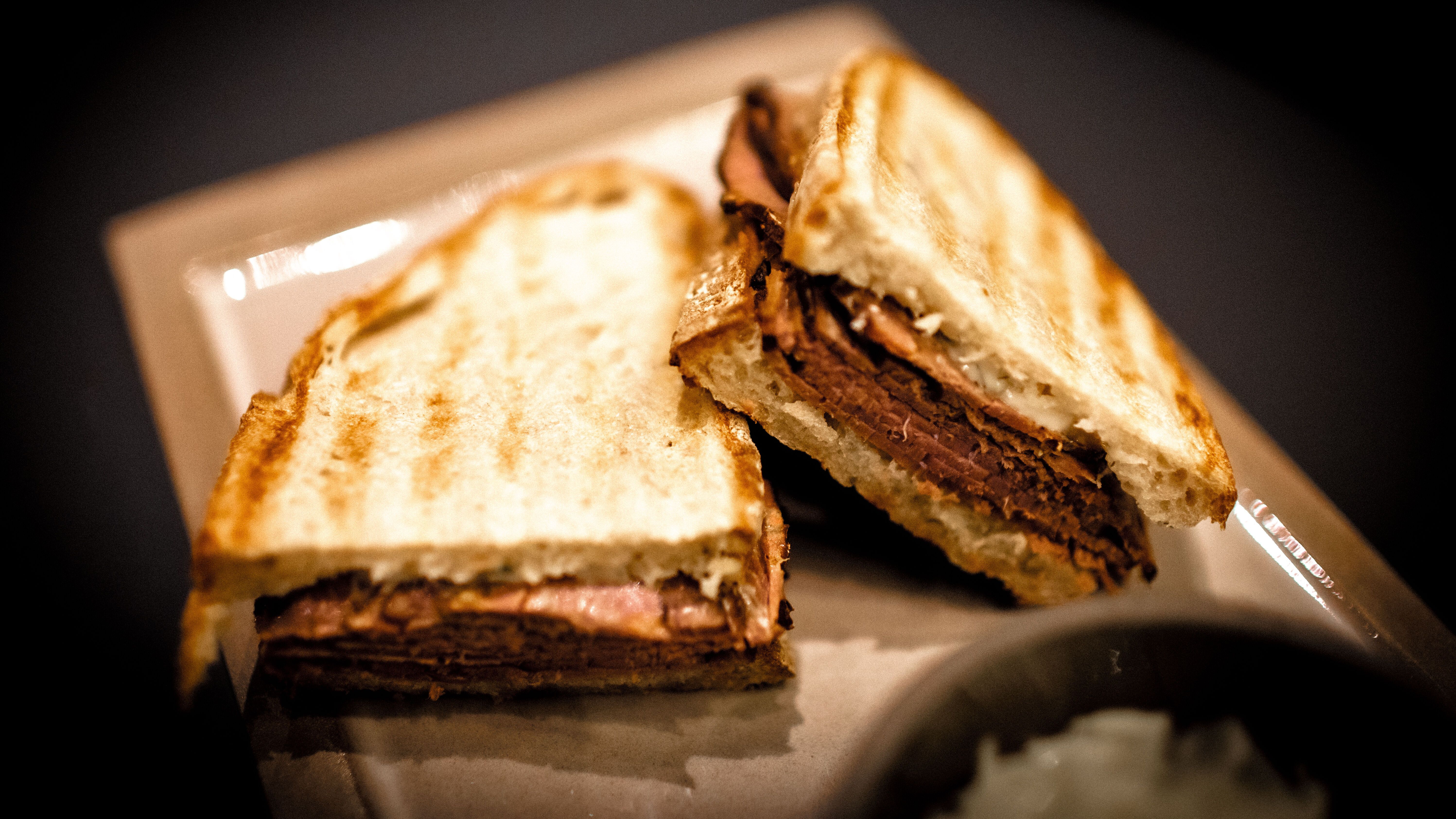 Gegrilltes Sandwich mit herzhaft gewürztem Fleisch, goldbraun geröstetem Brot, serviert auf einem Teller, ideal für eine sättigende Mahlzeit unterwegs oder in entspannter Atmosphäre.