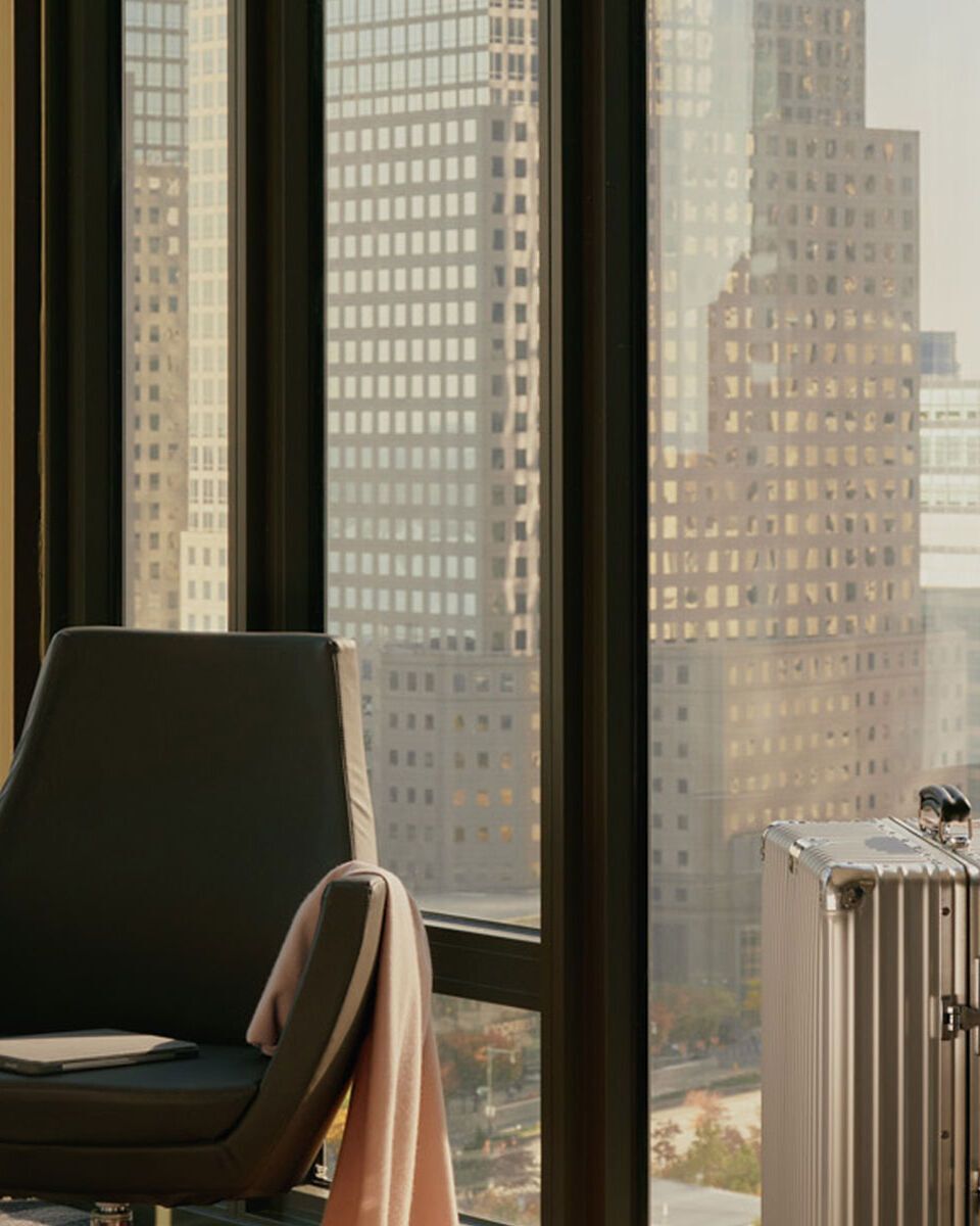 Modern eingerichteter Arbeitsplatz in Hotelzimmer mit Sitzgelegenheit, Schreibtisch und großem Fenster mit Stadtblick, ideal für Geschäftsreisende.