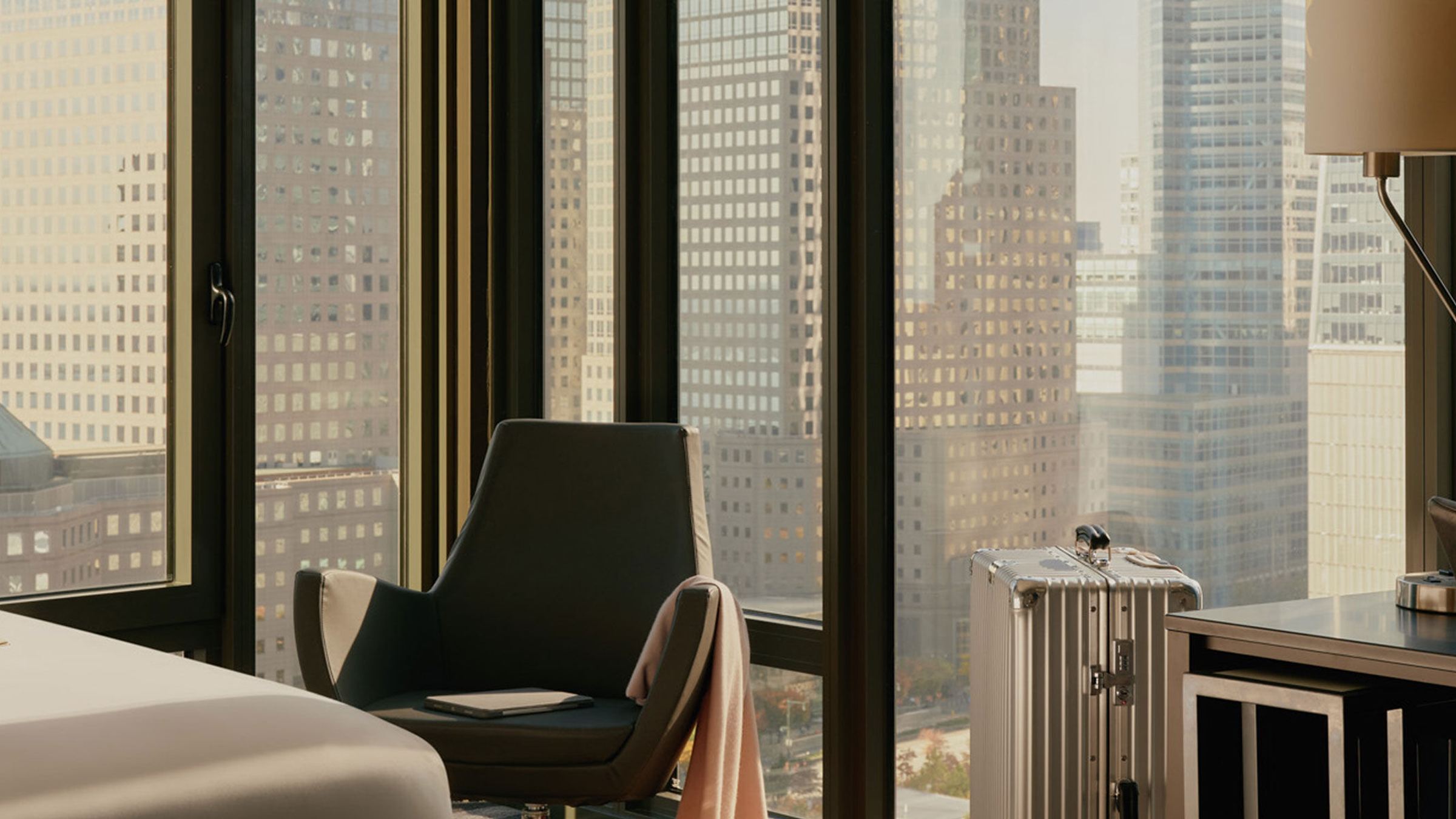 Modern eingerichteter Arbeitsplatz in Hotelzimmer mit Sitzgelegenheit, Schreibtisch und großem Fenster mit Stadtblick, ideal für Geschäftsreisende.