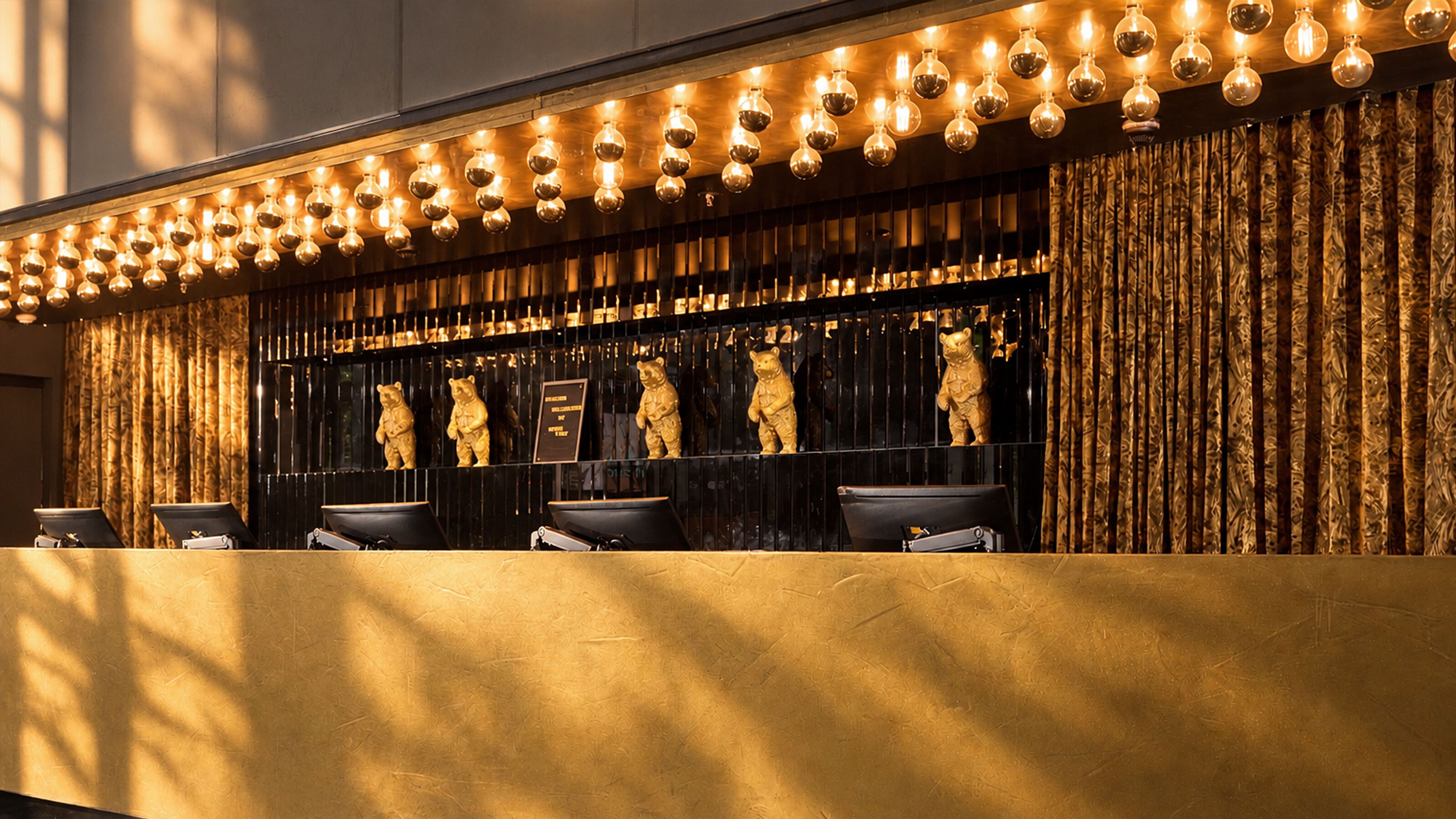 Rezeption mit warmem, goldenem Licht und dekorativen Bärenskulpturen, die eine einladende und elegante Atmosphäre schaffen.