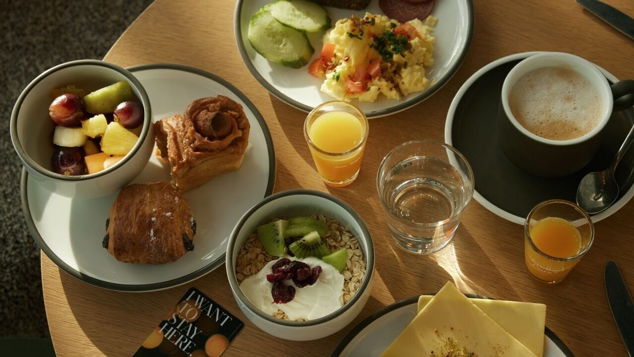 Frühstückstablett mit frischem Obstsalat, Gebäck, Müsli mit Joghurt und Kiwi, Rührei mit Gemüse, Brot, Wurst, Fruchtsäfte, Cappuccino und Wasser. Gemütliche, ausgewogene Mahlzeit für einen guten Start in den Tag. Frühstückstablett mit frischem Obstsalat, Gebäck, Müsli mit Joghurt und Kiwi, Rührei mit Gemüse, Brot, Wurst, Fruchtsäfte, Cappuccino und Wasser. Gemütliche, ausgewogene Mahlzeit für einen guten Start in den Tag.